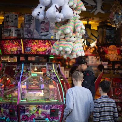 Zwei Kinder stehen vor einem .bunt beleuchteten Kirmesstand