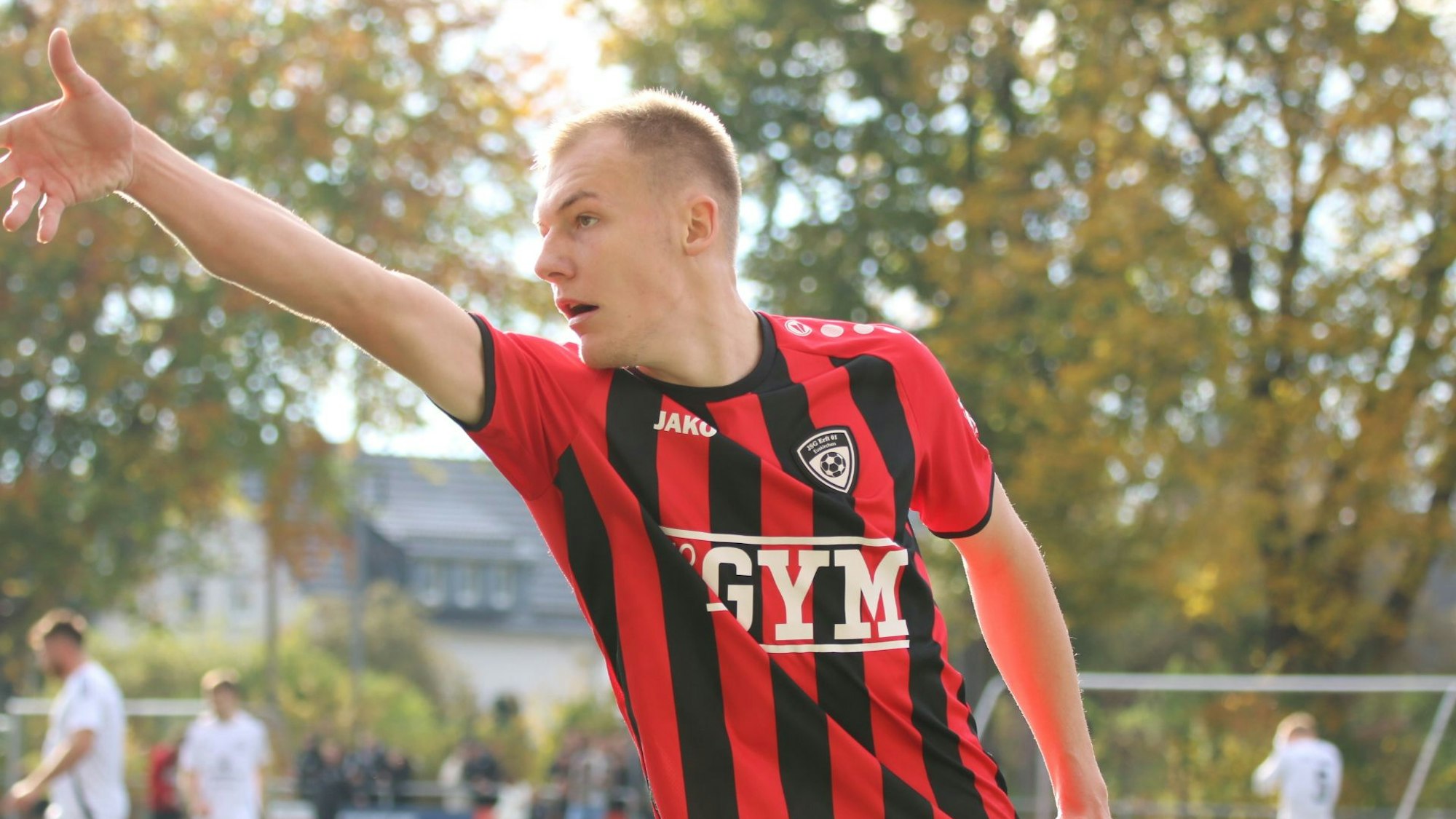Der Spieler Luke Bungart auf dem Fußballplatz. Er trägt das rot-schwarz-gestreifte Trikot seines Vereins.