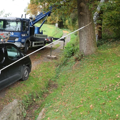 Ein Imker in Schutzanzug hält eine vier Meter lange Lanze mit einem Gift in den Händen.