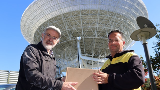 Das Bild zeigt die beiden Obengenannten, die gemeinsam ein Paket in den Händen halten.