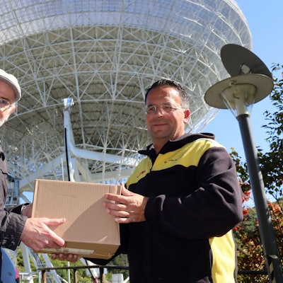 Das Bild zeigt die beiden Obengenannten, die gemeinsam ein Paket in den Händen halten.