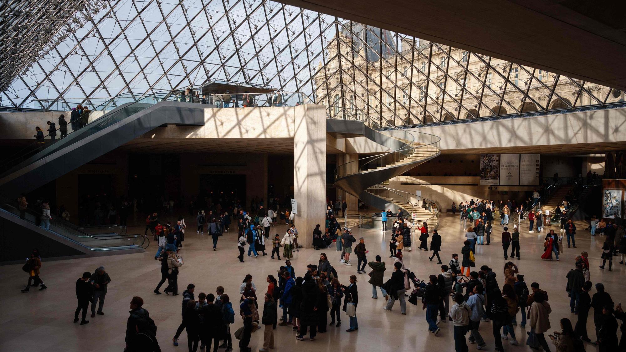Besucher gehen unter der Louvre-Pyramide im Louvre-Museum in Paris hindurch. (Symbolbild)