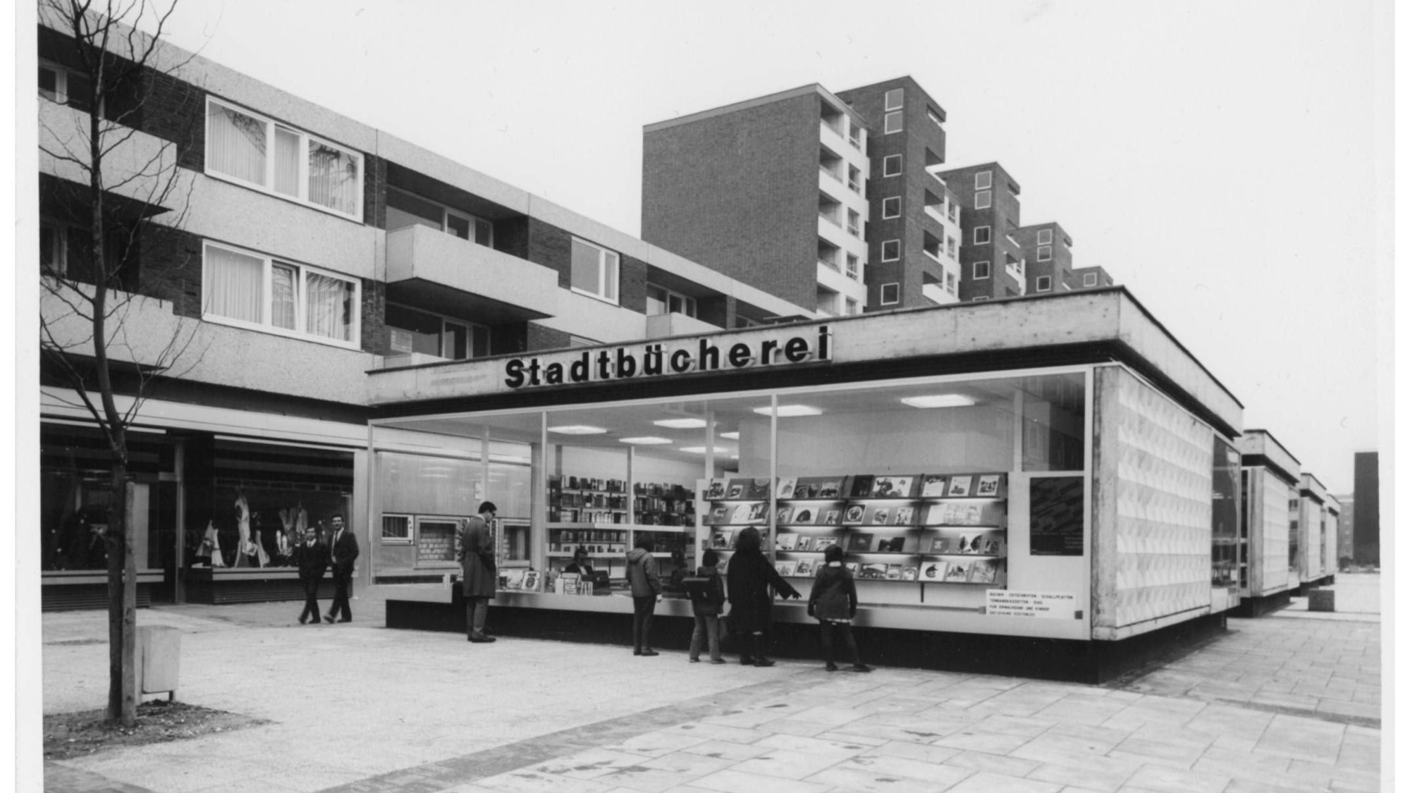 Ein Flachdachgebäude vor einer Hochhauskulisse.