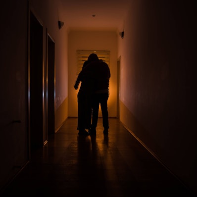 Dunkler Korridor mit Schranktüren und Lichtern mit der Silhouette eines gespenstischen Horror-Mannes, der in verschiedenen Posen steht.