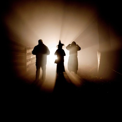 Drei Personen stehen im Gegenlicht, von ihnen sind nur die Umrisse zu erkennen.