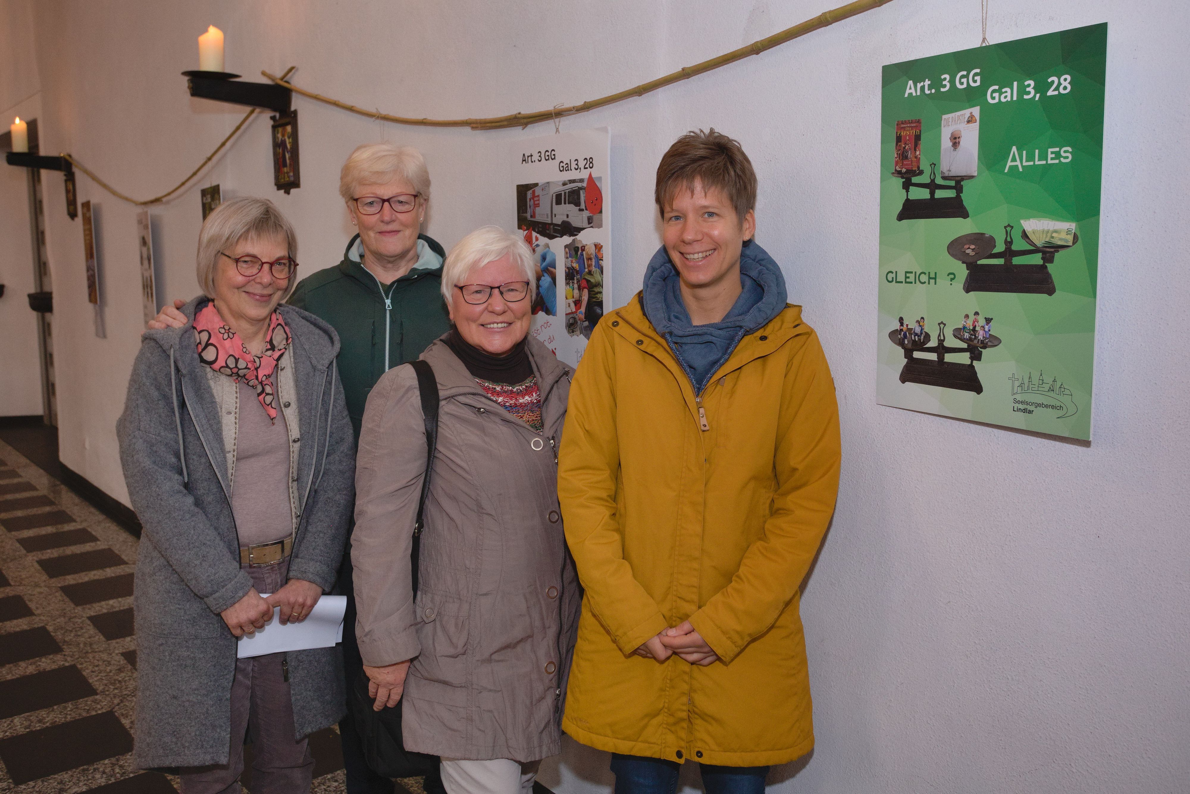 Vier Frauen stehen in einer Kirche vor den Plakaten der Ausstellung.