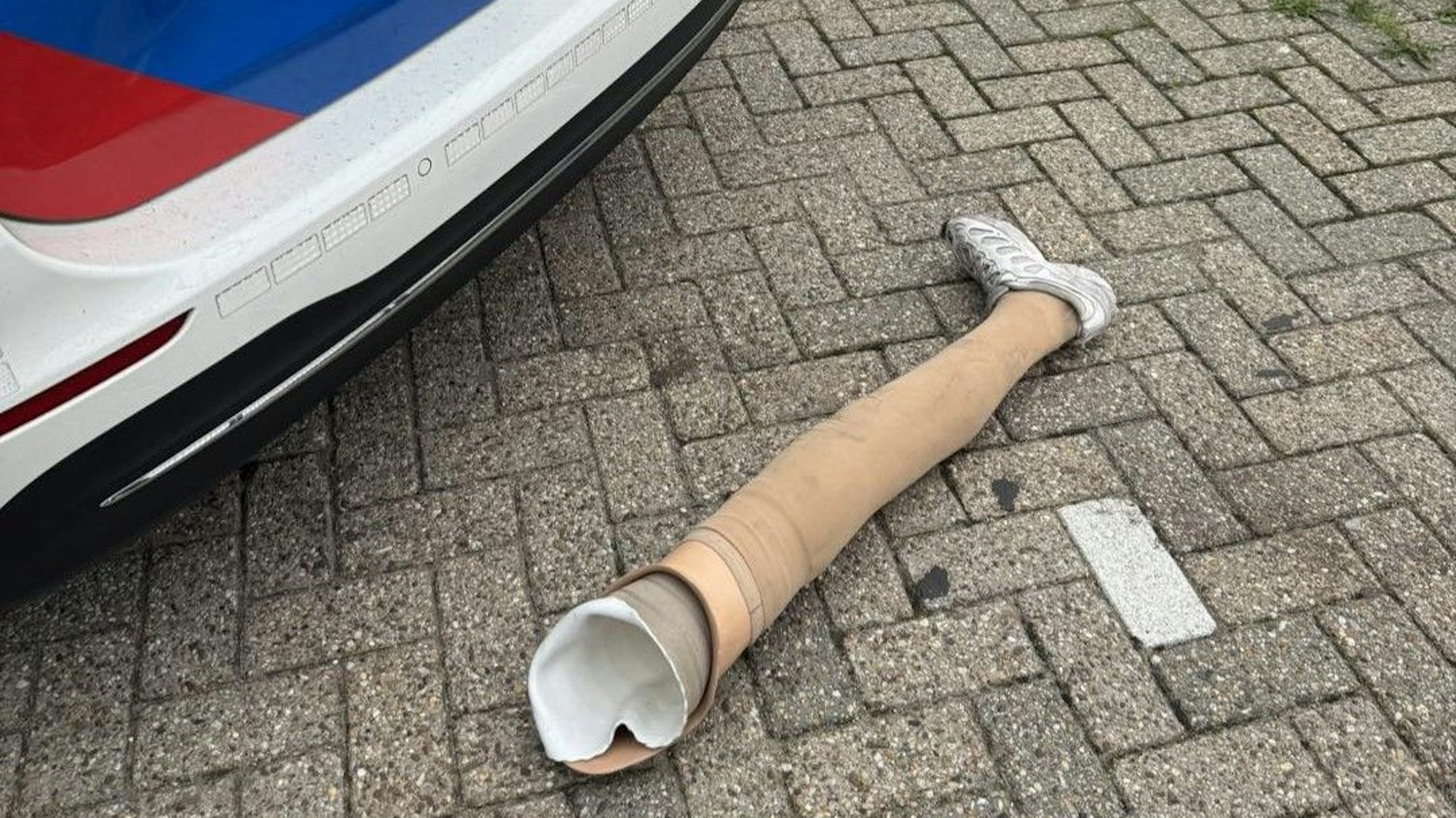 Das Bein eines mutmaßlichen Ladendiebs liegt vor einem Polizeiauto auf der Straße.