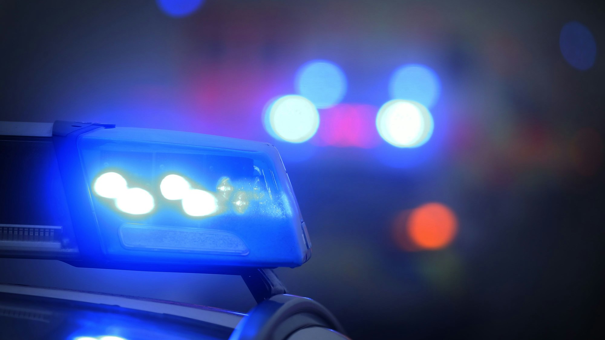 Ein Polizeiauto mit eingeschaltetem Blaulicht steht an einer Unfallstelle.