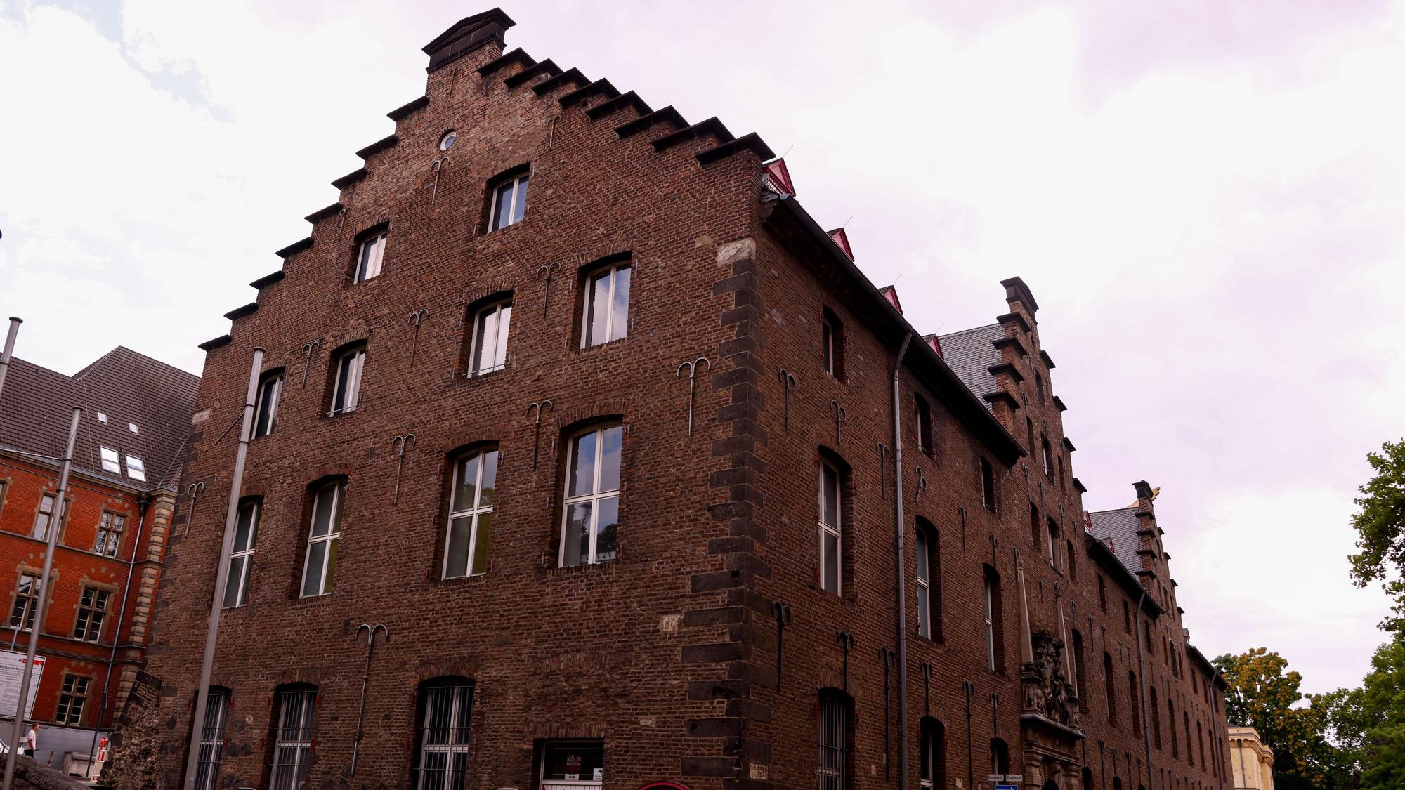 28.07.2025, Köln: Die rot-weißen Fensterläden am Zeughaus, in der Fachsprache Schlagläden genannt, wurden seit Montag abgenommen, weil sie marode sind. Das Gebäude zeigt sich jetzt ohne die Fensterläden. Foto: Thilo Schmülgen