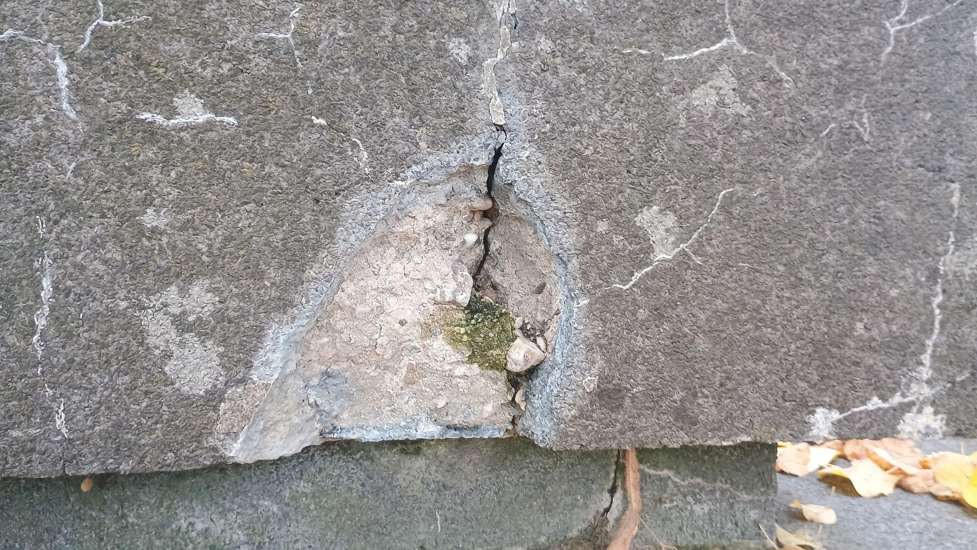 Das Bild zeigt die Risse im Stein und ein Loch, wo ein Stück des Podests herausgebrochen ist.