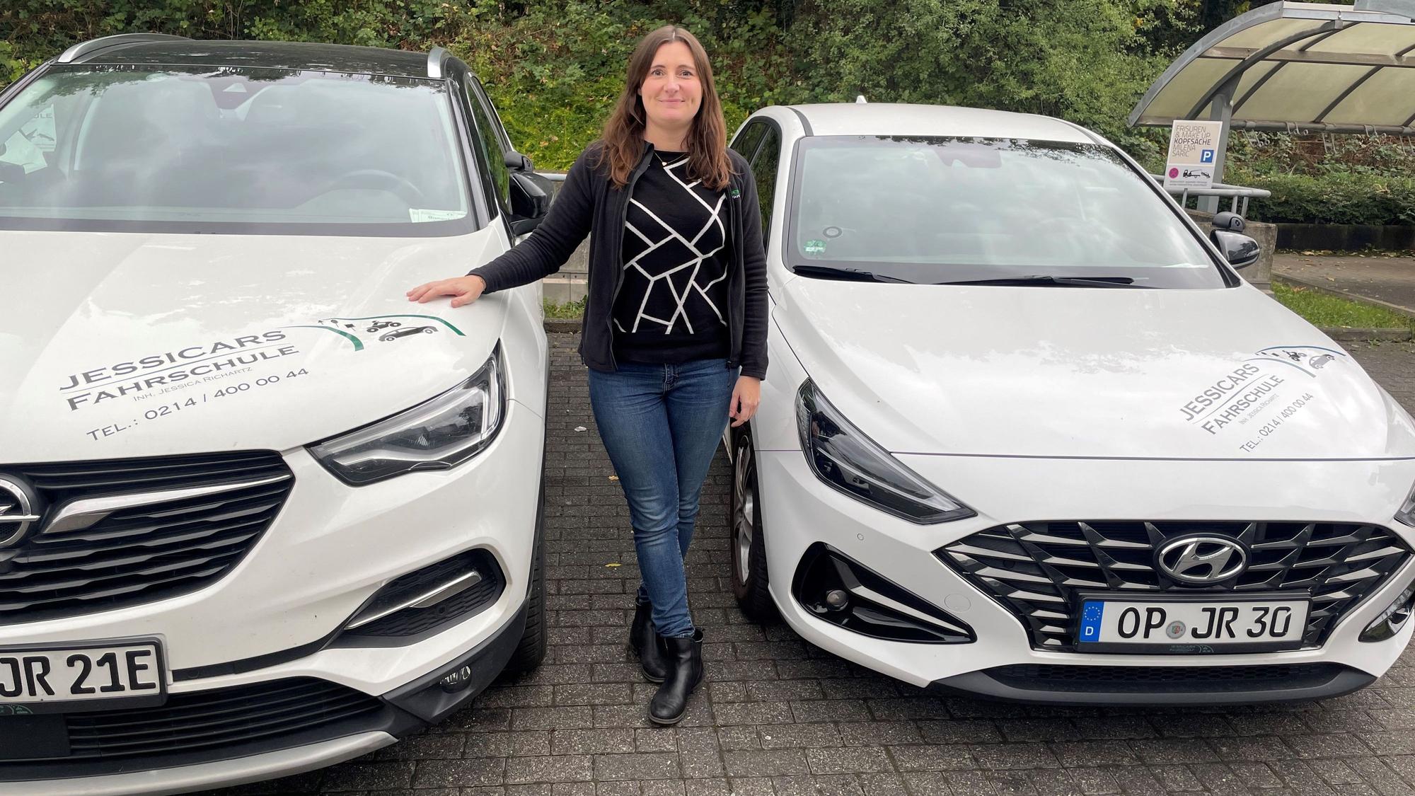 Jessica Richartz zwischen zwei ihrer Fahrschul-Autos.