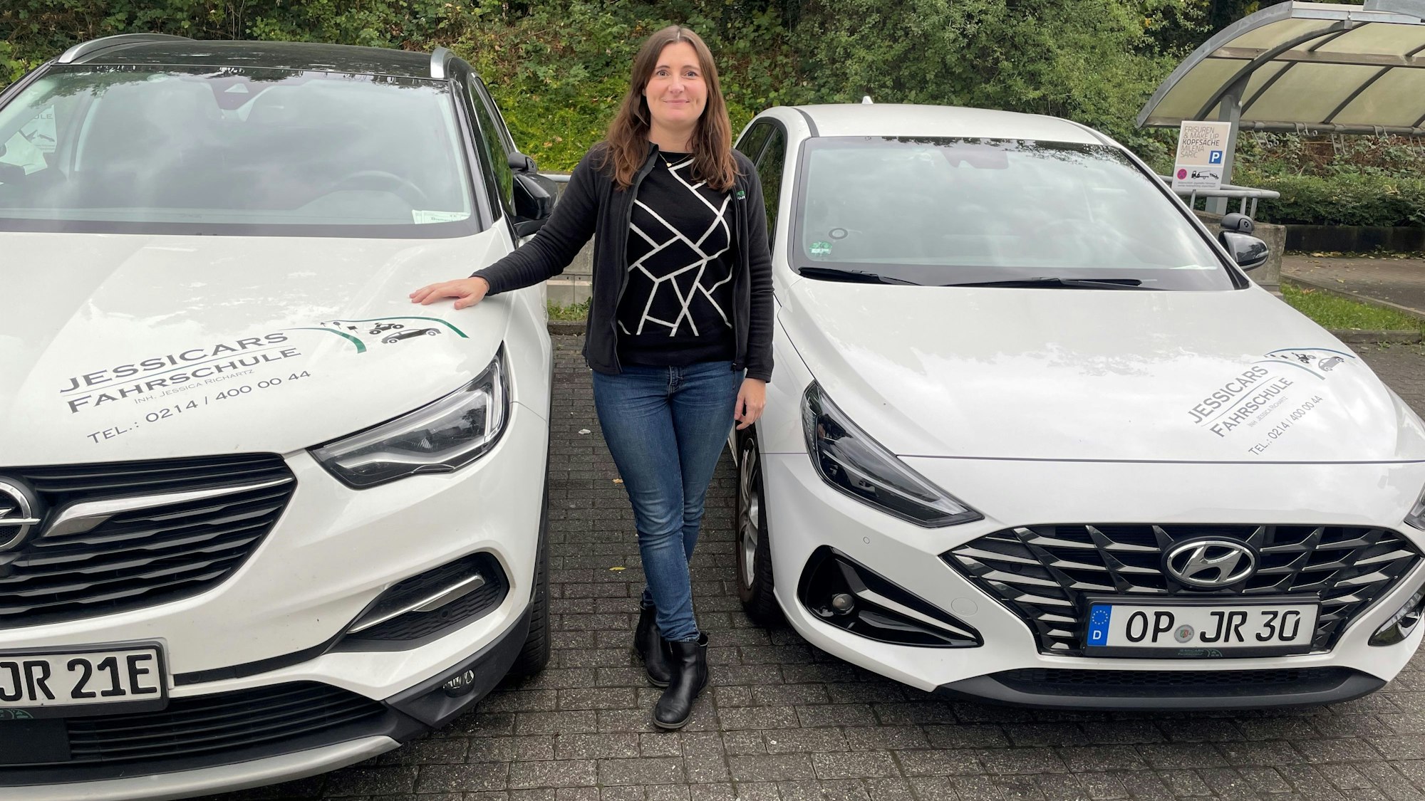 Jessica Richartz zwischen zwei ihrer Fahrschul-Autos.