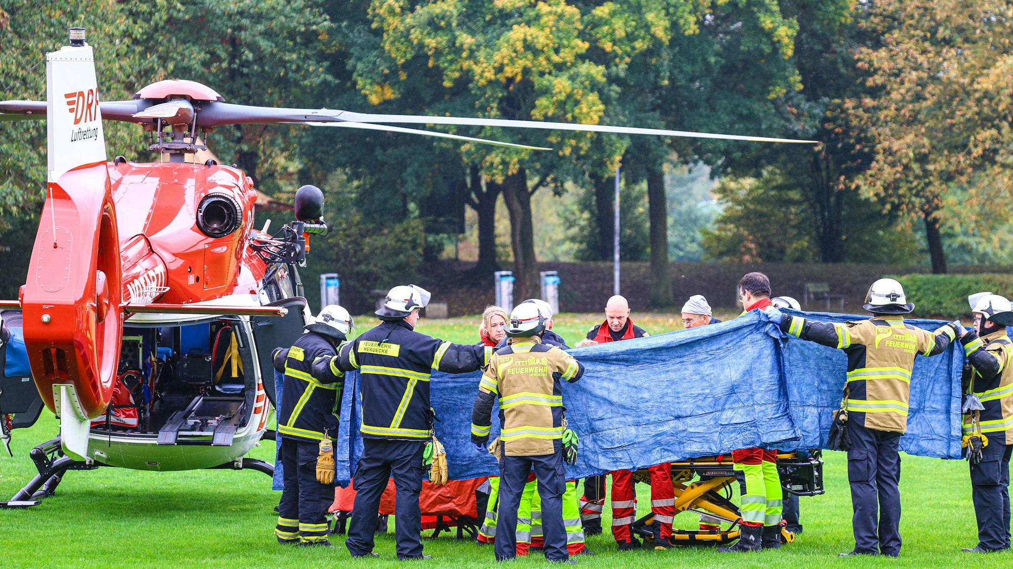 Einsatzkräfte stehen neben einem Rettungshubschrauber. Die neu gewählte Bürgermeisterin von Herdecke, Iris Stalzer (SPD), ist lebensgefährlich verletzt in ihrer Wohnung gefunden worden. Sie habe mehrere Messerstiche erlitten, hieß es aus Sicherheitskreisen. Foto: Alex Talash/dpa