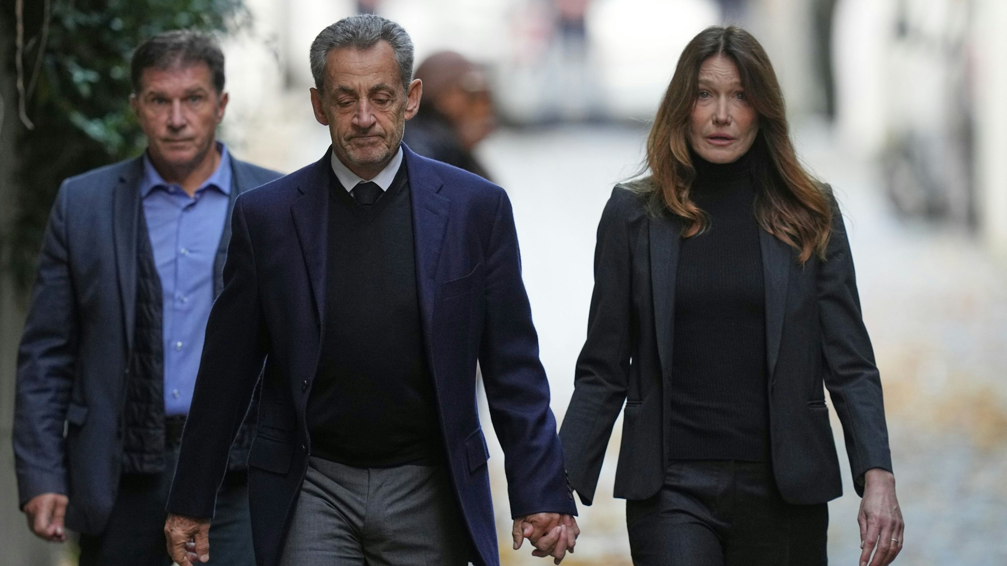 Nicolas Sarkozy und seine Frau Carla Bruni-Sarkozy gehen Hand in Hand die Straße runter.
