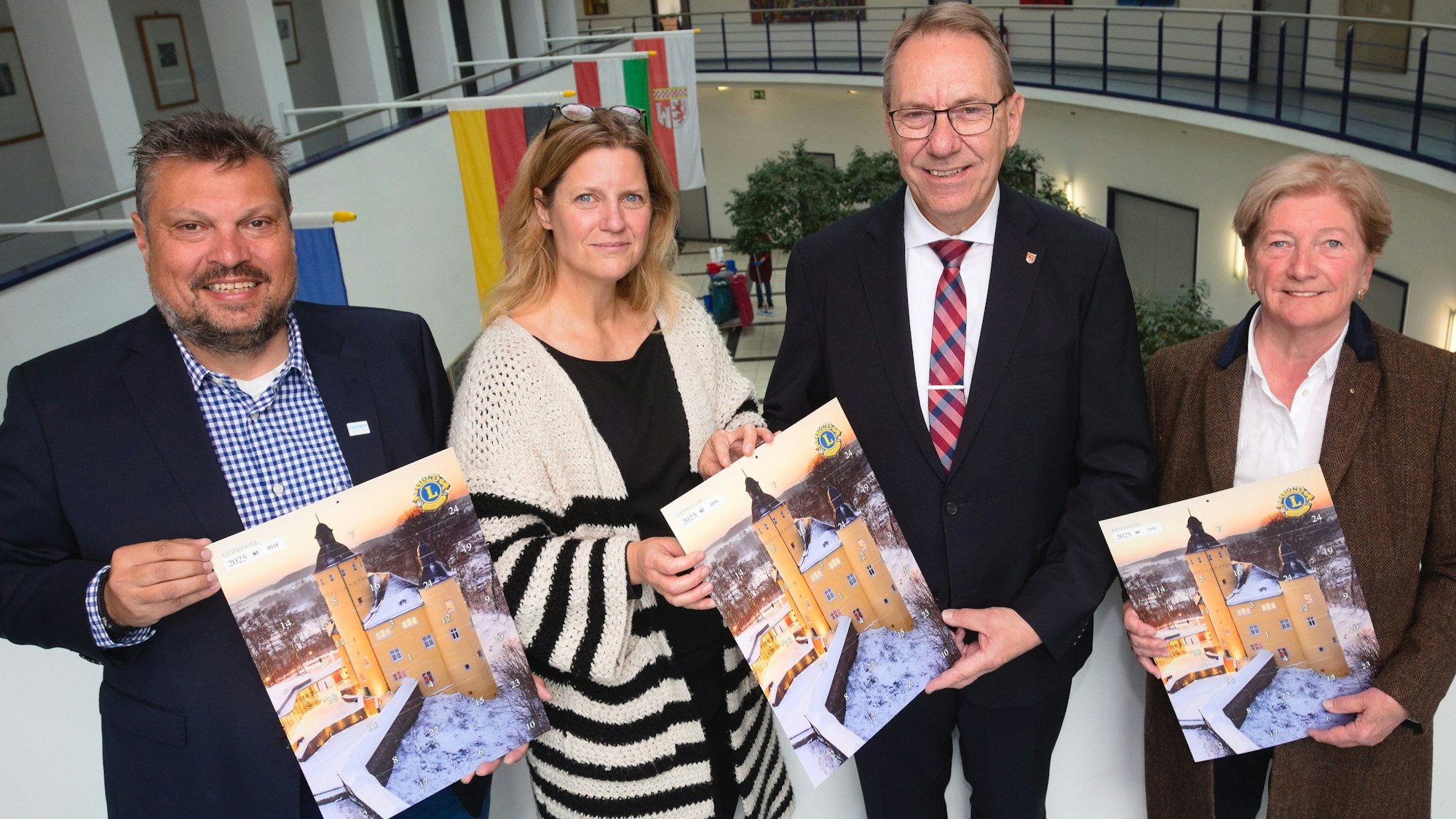 Das Schloss Homburg im Schnee ziert den neuen Adventskalender, der jetzt von (von links) Unternehmer Timo Fuchs, Klinikum-Sprecherin Angela Altz, Landrat Jochen Hagt und Apothekerin Gudrun von Scheven im Gummersbacher Kreishaus vorgestellt worden ist.