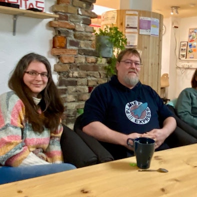 Die vier Peer-Berater des SPZ sitzen an einem Tisch und schauen zur Kamera.