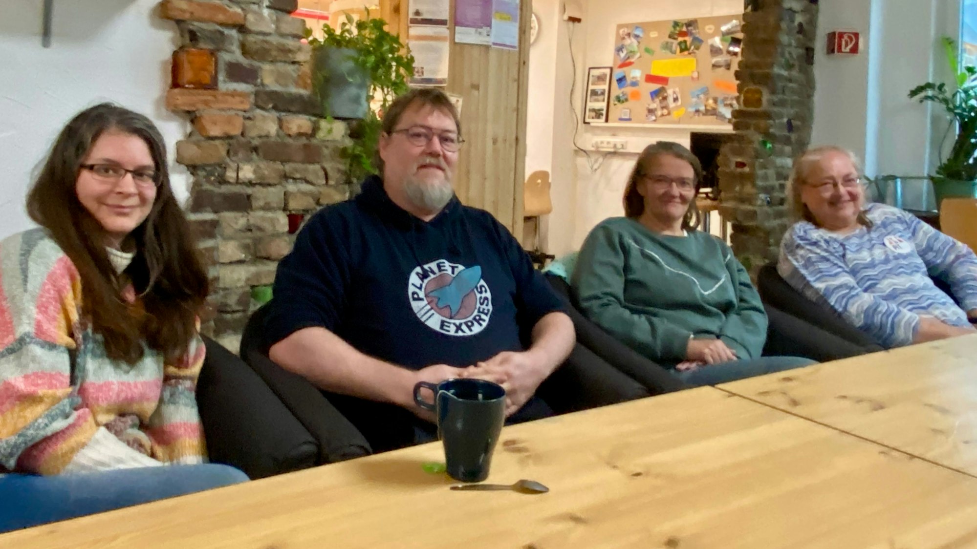 Die vier Peer-Berater des SPZ sitzen an einem Tisch und schauen zur Kamera.