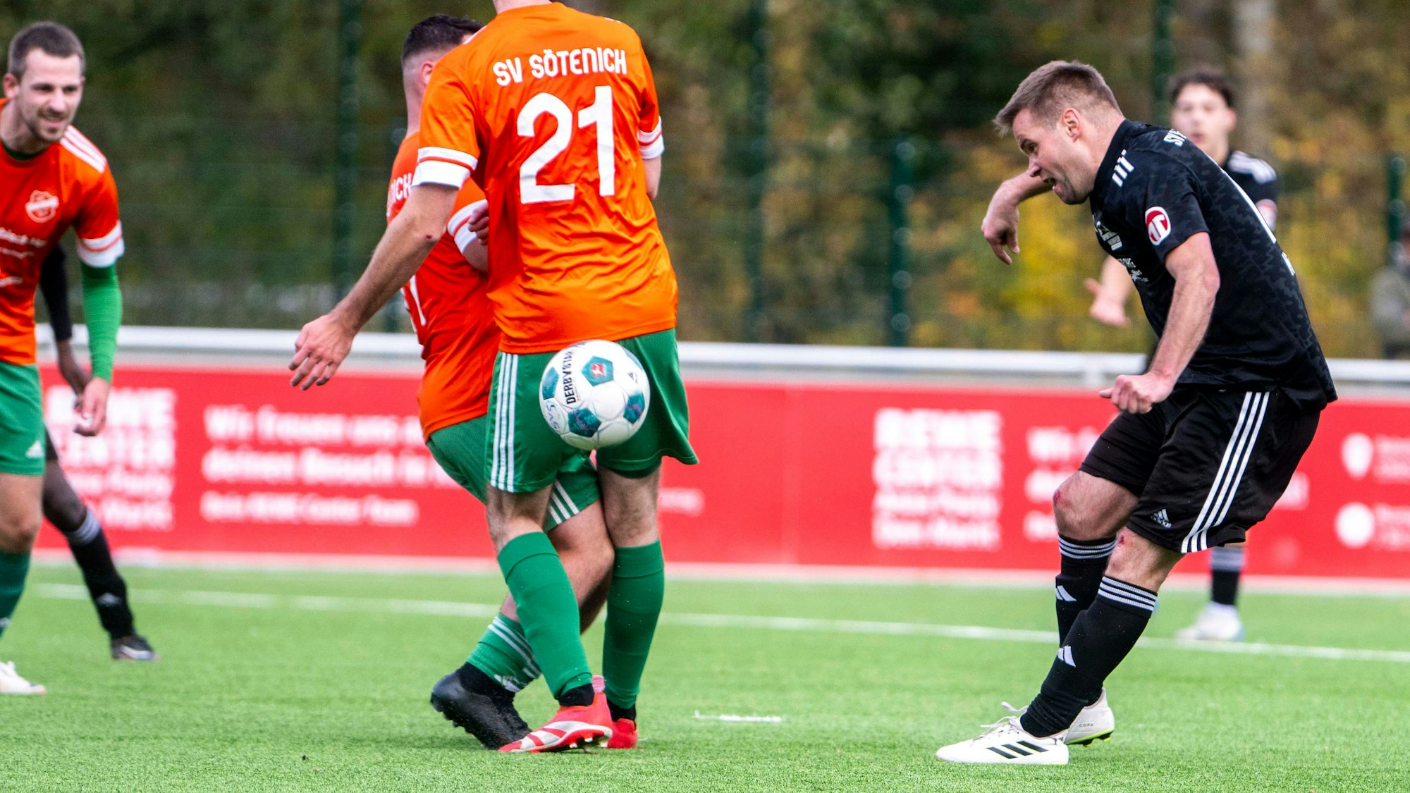 Michael Jansen spielt einen Ball hinter dem Rücken zweier Sötenicher Spieler, die sich gegenseitig behindern.