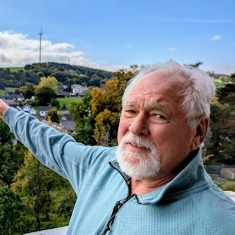 Der Kallmuther Ortsbürgermeister Robert Ohlerth deutet auf den südlich des Ortes gelegenen Windpark am Ravelsberg.