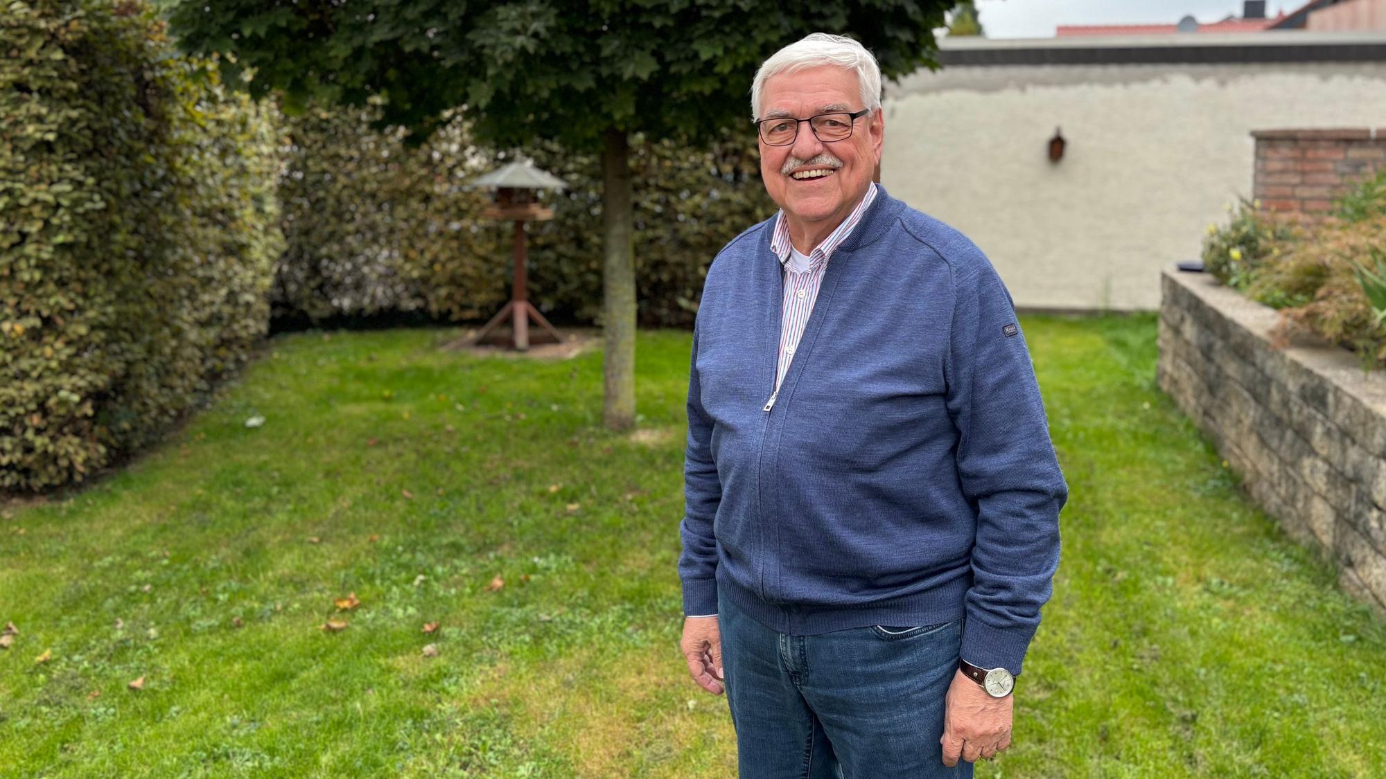 Hans Peter Nußbaum steht in einem Garten auf der Wiese.