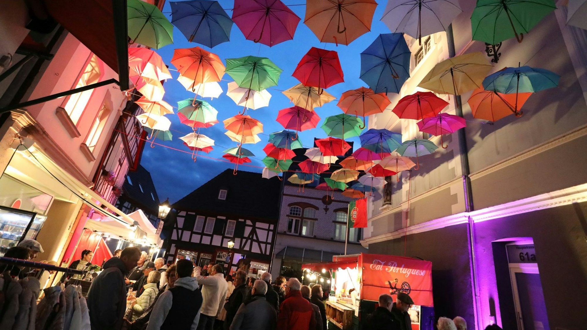 Über einer Straße sind nach mediterranem Vorbild bunte Schirme gespannt.