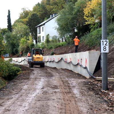 Ein Bagger fährt entlang der Stützmauer. Die Gleise in dem Bereich der Erfttalbahn fehlen. Auf der Mauer steht ein Arbeiter und telefoniert.