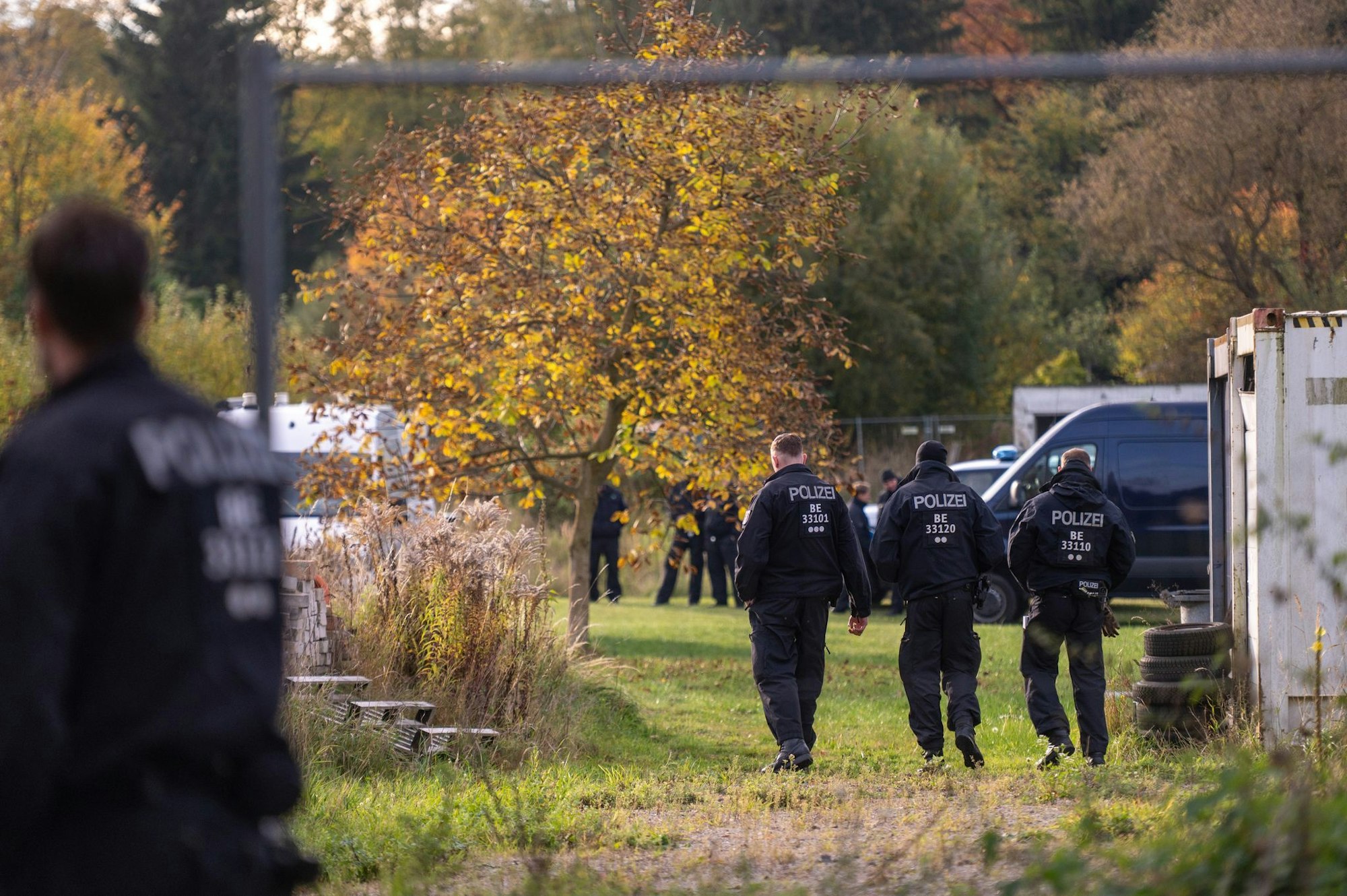 Polizisten stehen bei dem Großeinsatz auf einem Grundstück. (Archivbild)