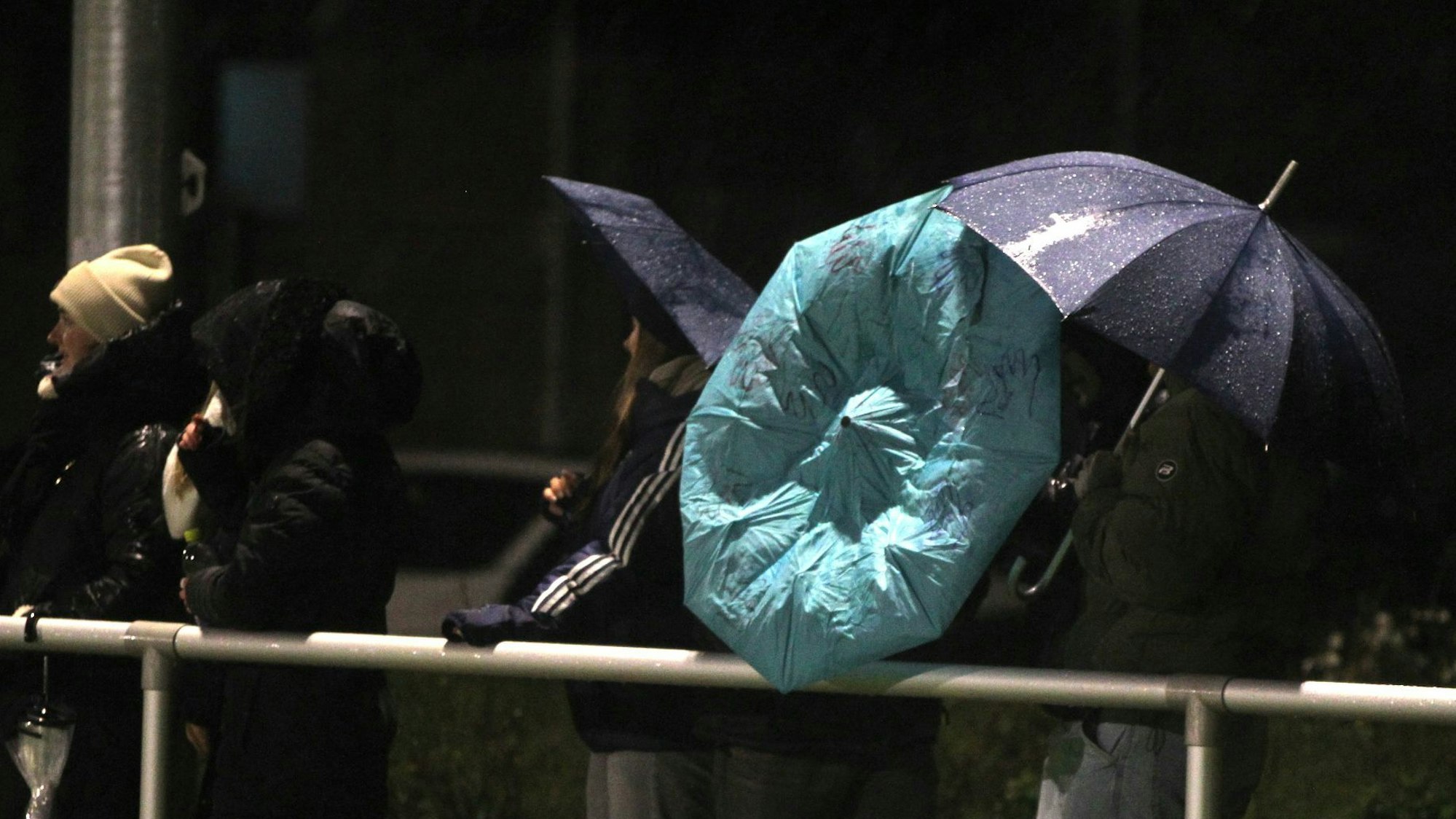 Zuschauer suchen unter Regenschirmen Schutz, doch die geben unter der Wucht des Sturms nach.