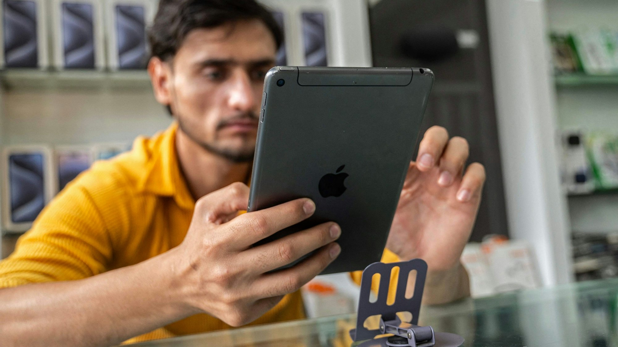 Ein Mann sitzt an einem Tisch und benutzt ein iPad.