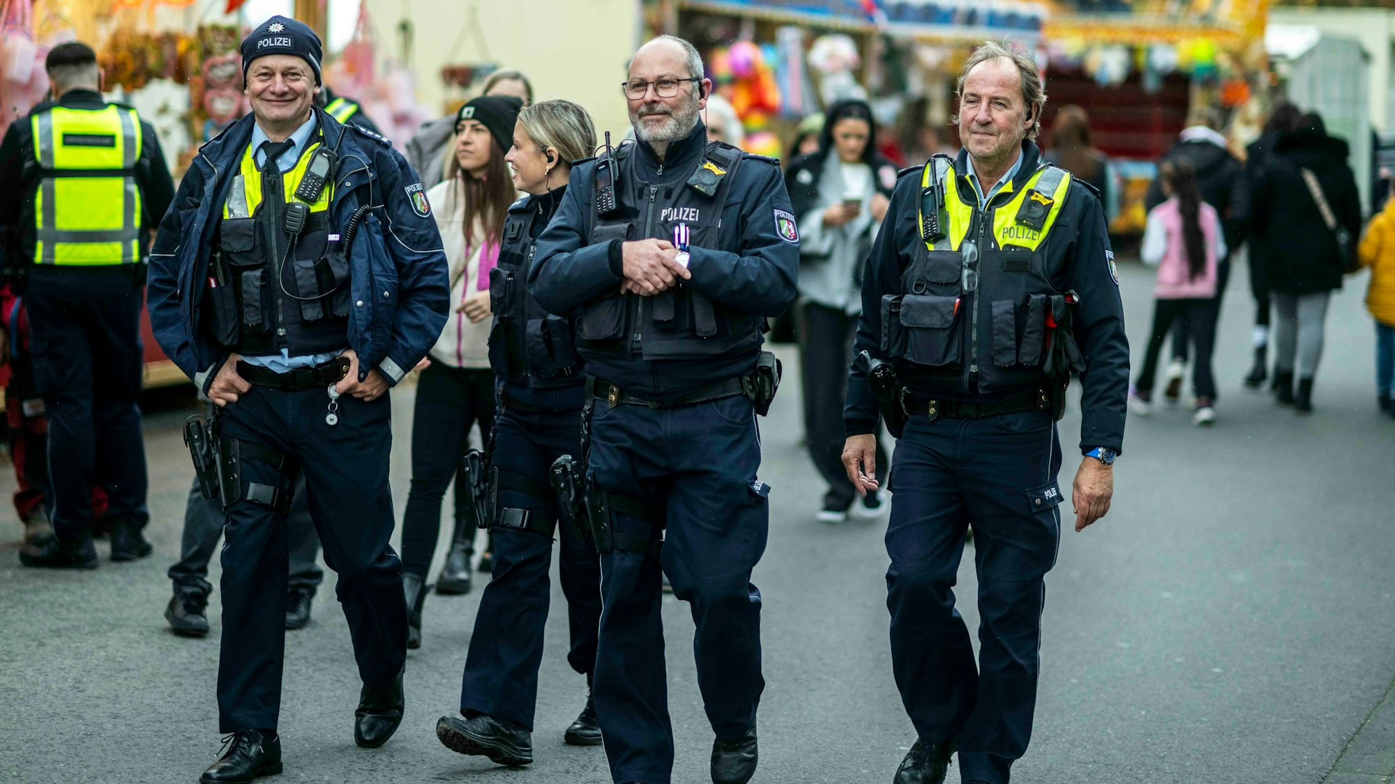 Das Bild zeigt einige Polizeibeamte, die über die Kirmes schlendern.