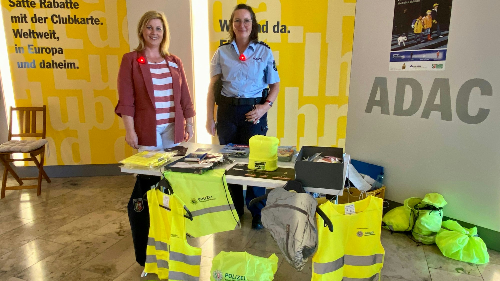 Simone Hansen und Lydia Hüpgen stehen hinter einem Tisch, auf dem Sicherheitszubehör arrangiert ist.