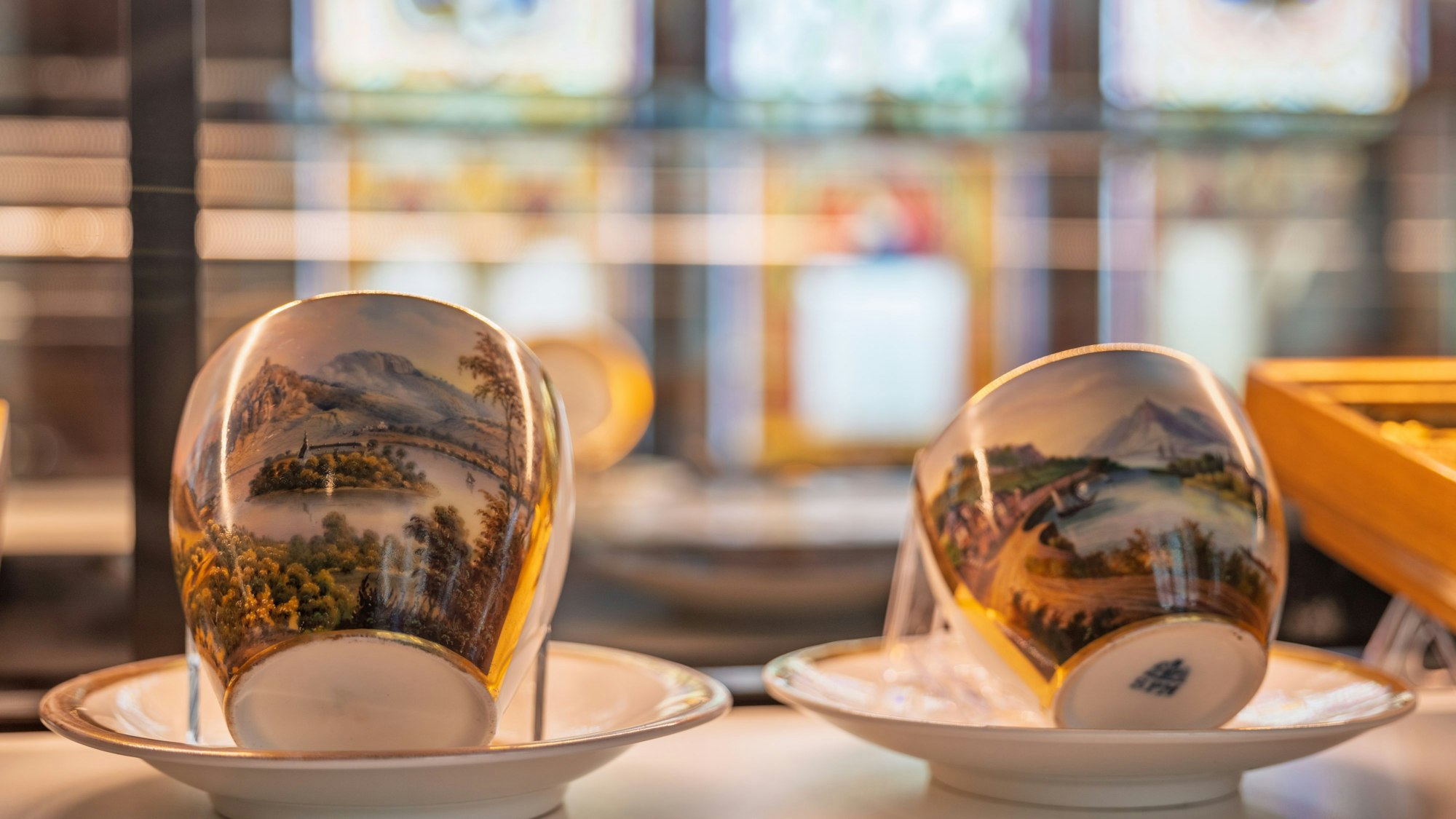 Zwei Porzellantassen mit Landschaftsdarstellungen.