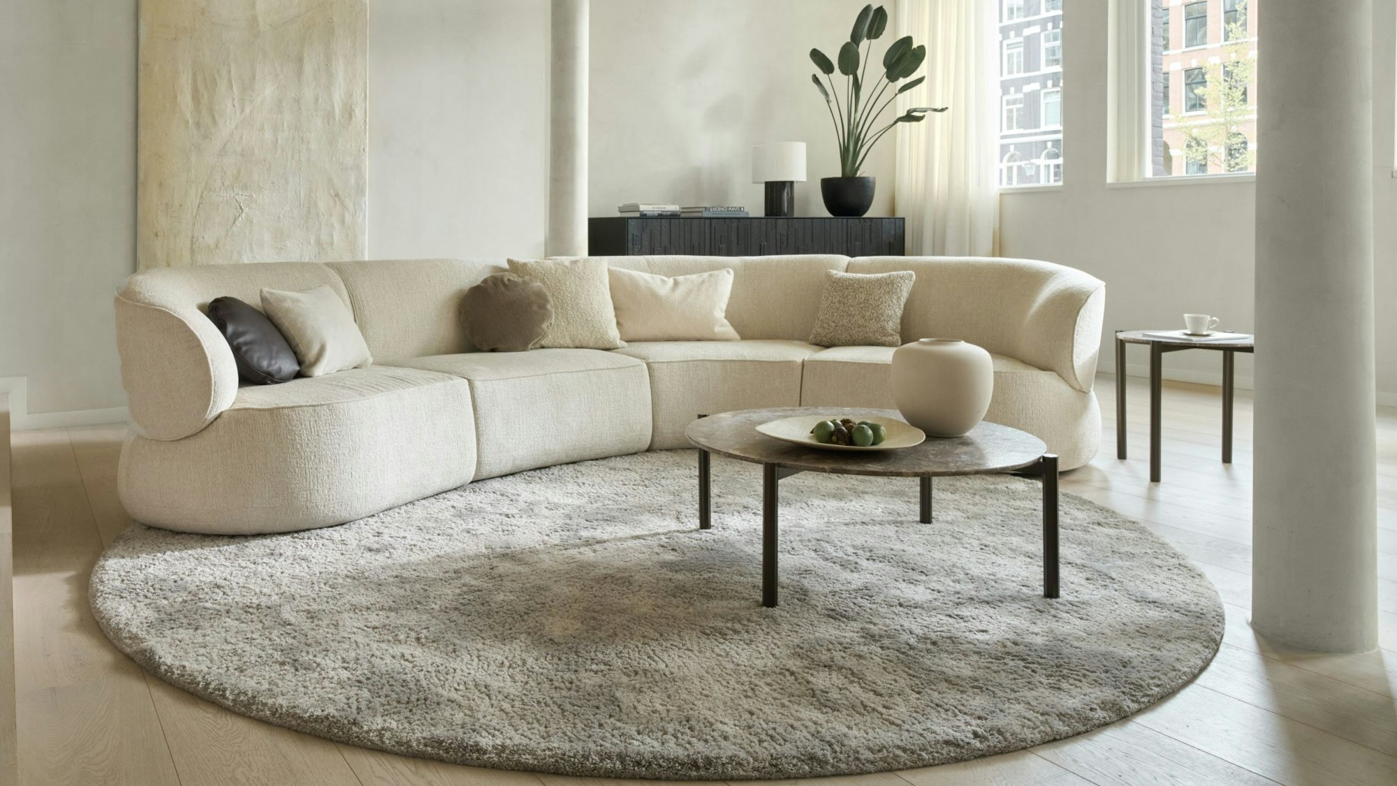 Ein beiges Sofa steht auf einem grauen Teppich