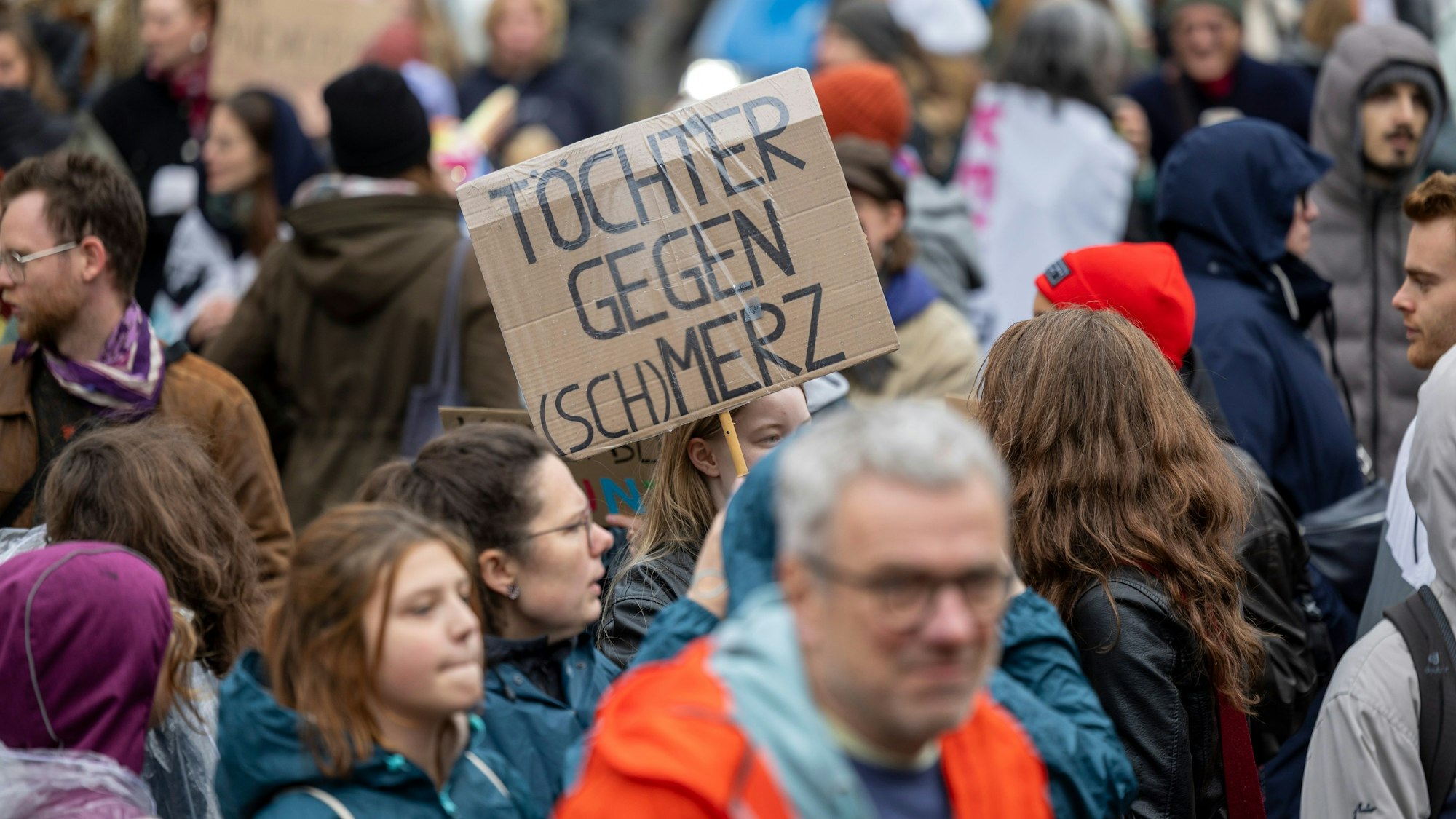 Eine Teilnehmerin der Kundgebung hält ein Schild hoch mit der Aufschrift: „Töchter gegen (Sch)Merz“