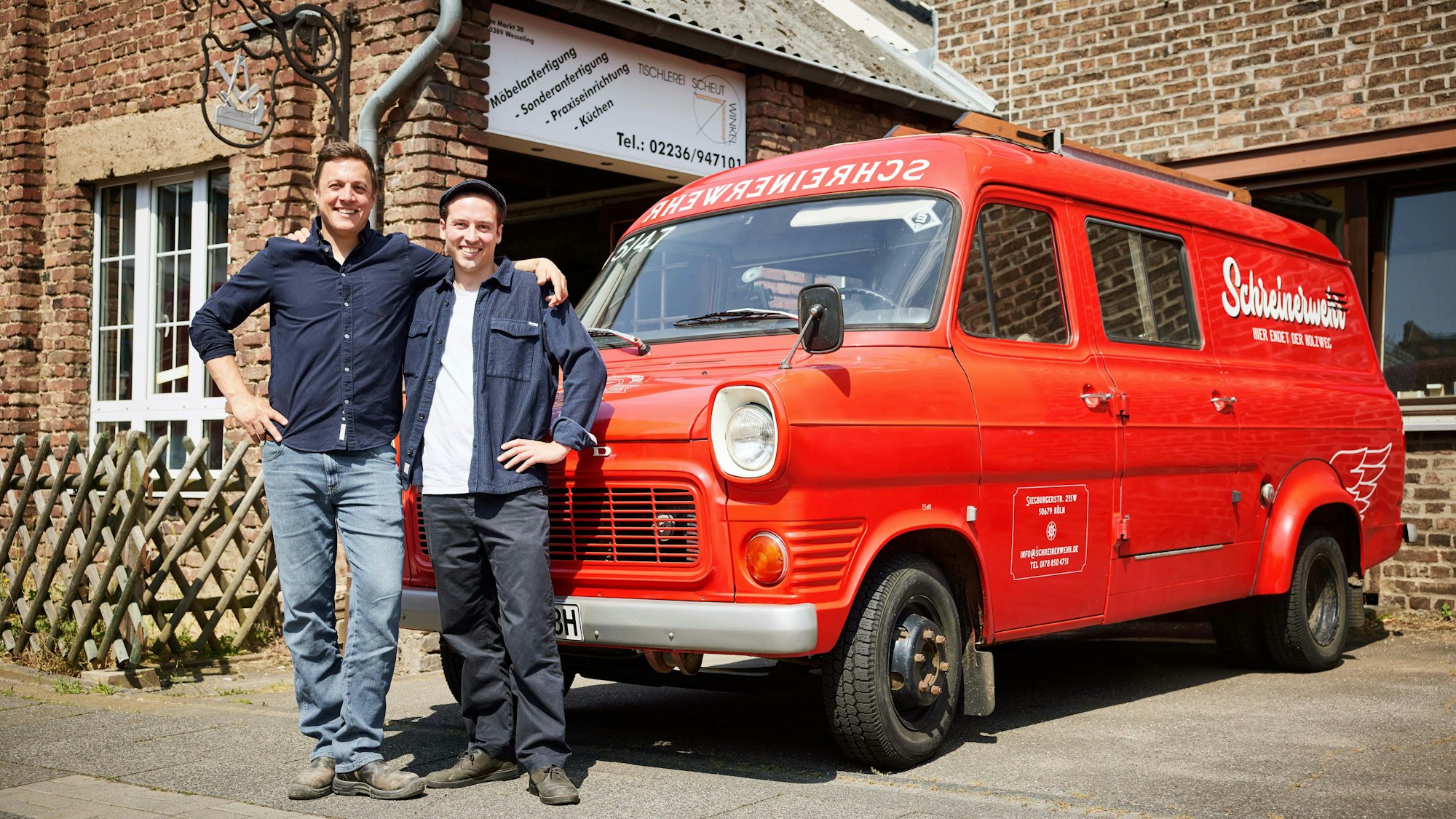 Zwei Männer stehen vor einem roten Auto.