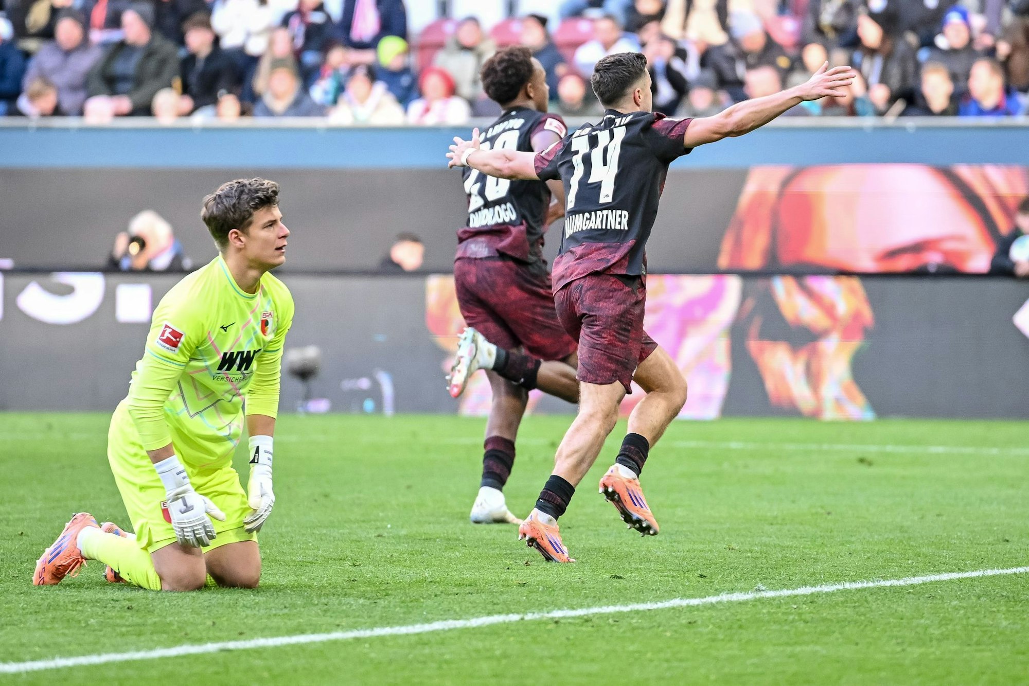 Augsburgs Torwart Finn Dahmen kauert bedröppelt am Boden, die Leipziger Assan Quedraogo (M) und Christoph Baumgartner (r) bejubeln das 0:5.
