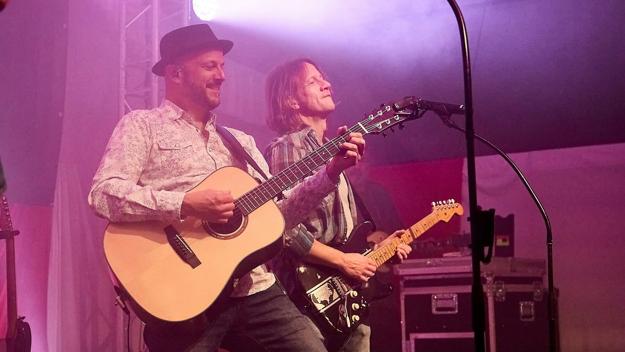 Zwei Gitarristen spielen nebeneinander auf der Bühne.