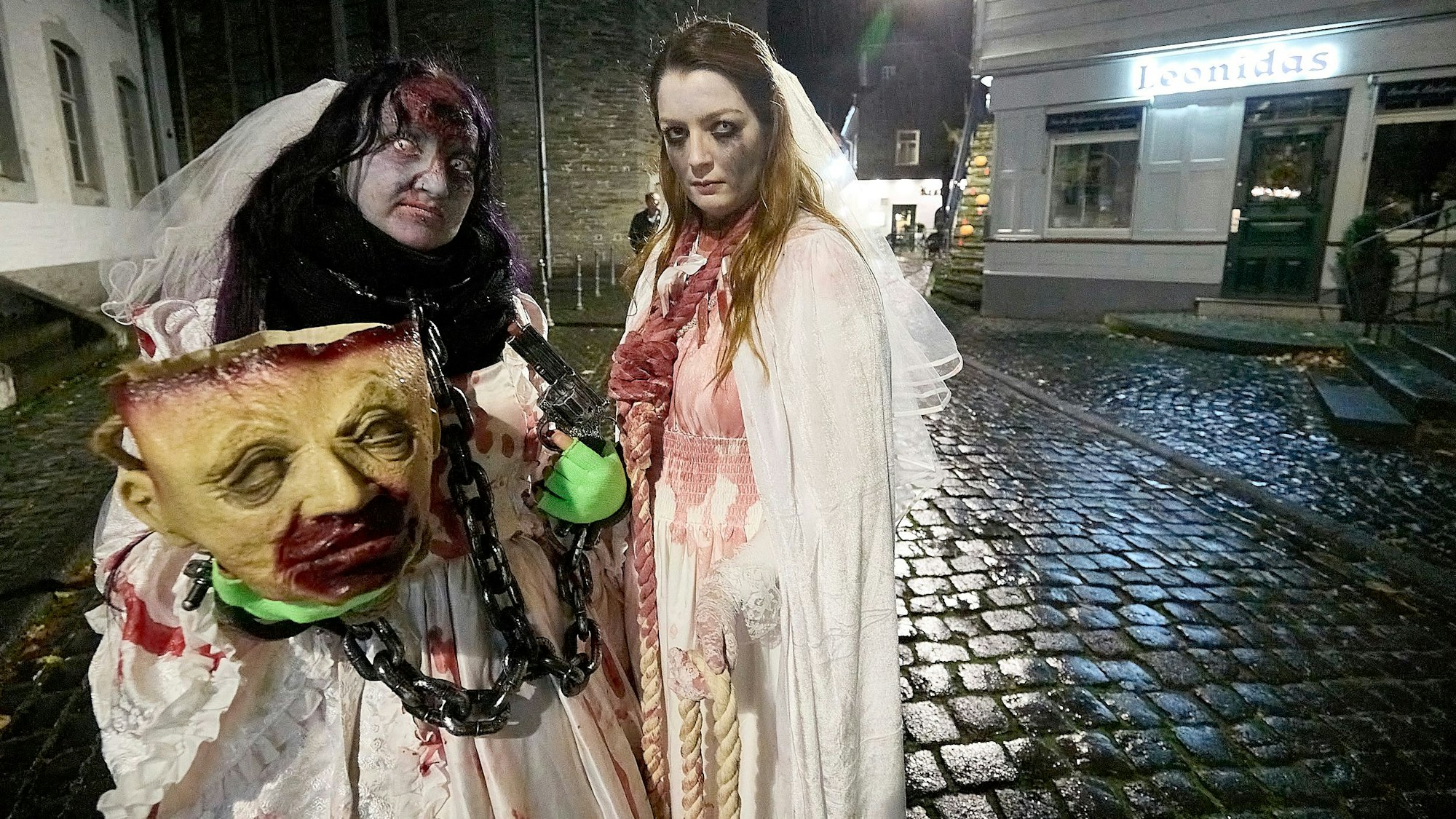 Zwei Personen in hellen Kostümen und mit bemalten Gesichtern laufen durch Monschau.