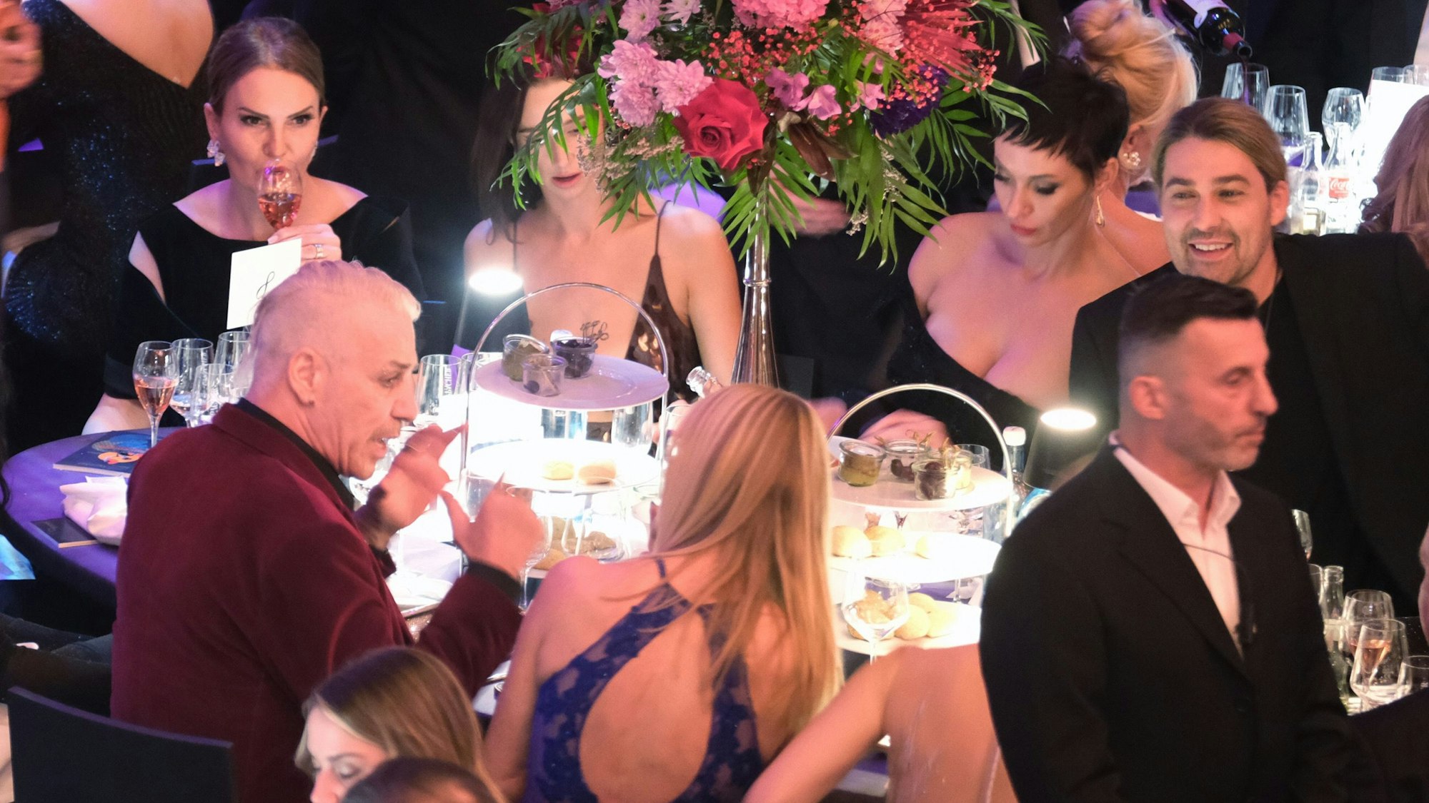 Das Bild zeigt Till Lindemann (l), Sänger der Band Rammstein, beim Leipziger Opernball an einem Tisch, rechts ist Star-Geiger David Garrett zu sehen. Foto: Sebastian Willnow/dpa