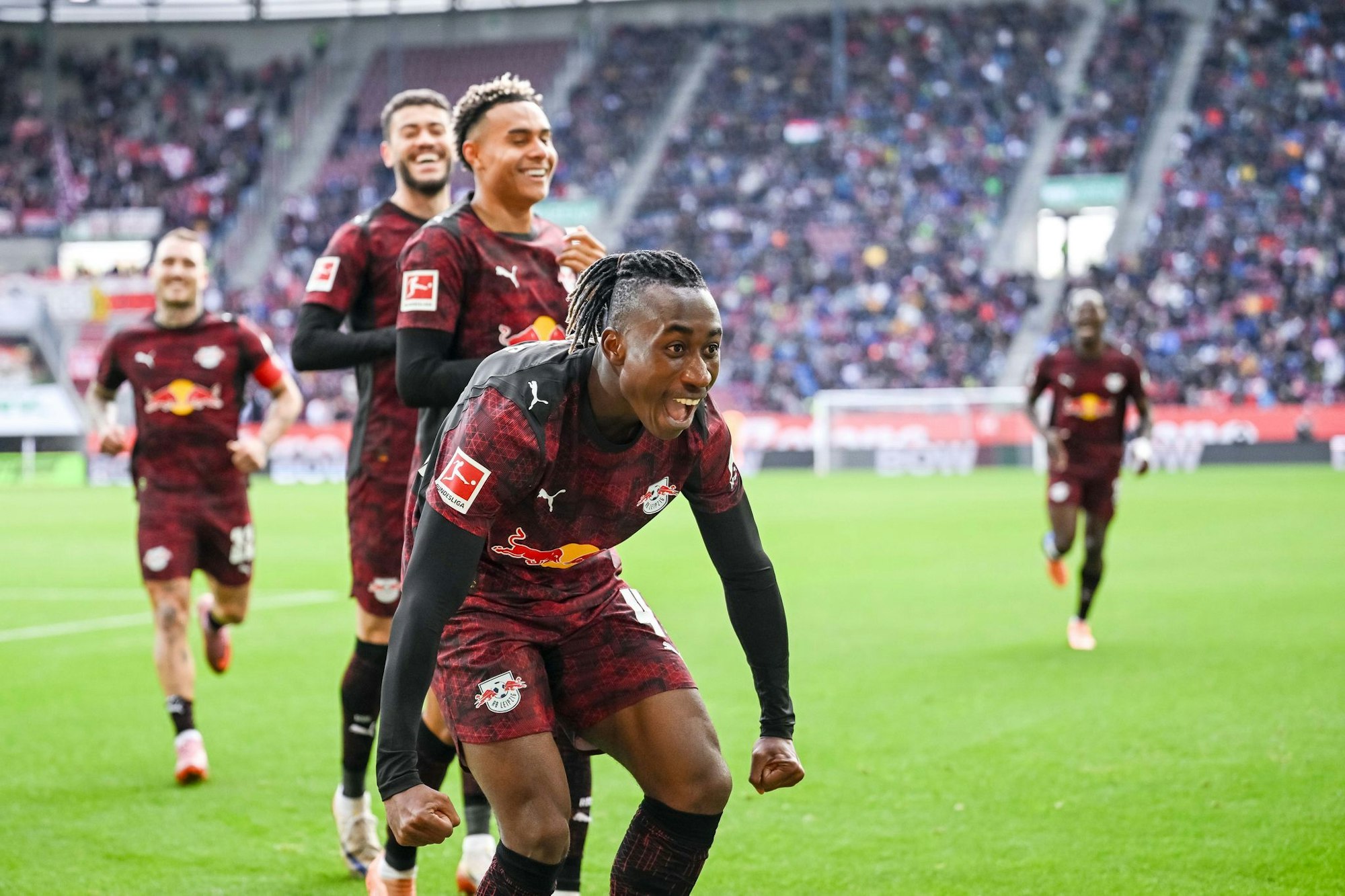 Glückliche Leipziger, vorne 1:0-Schütze Yan Diomande, jubeln in Augsburg.