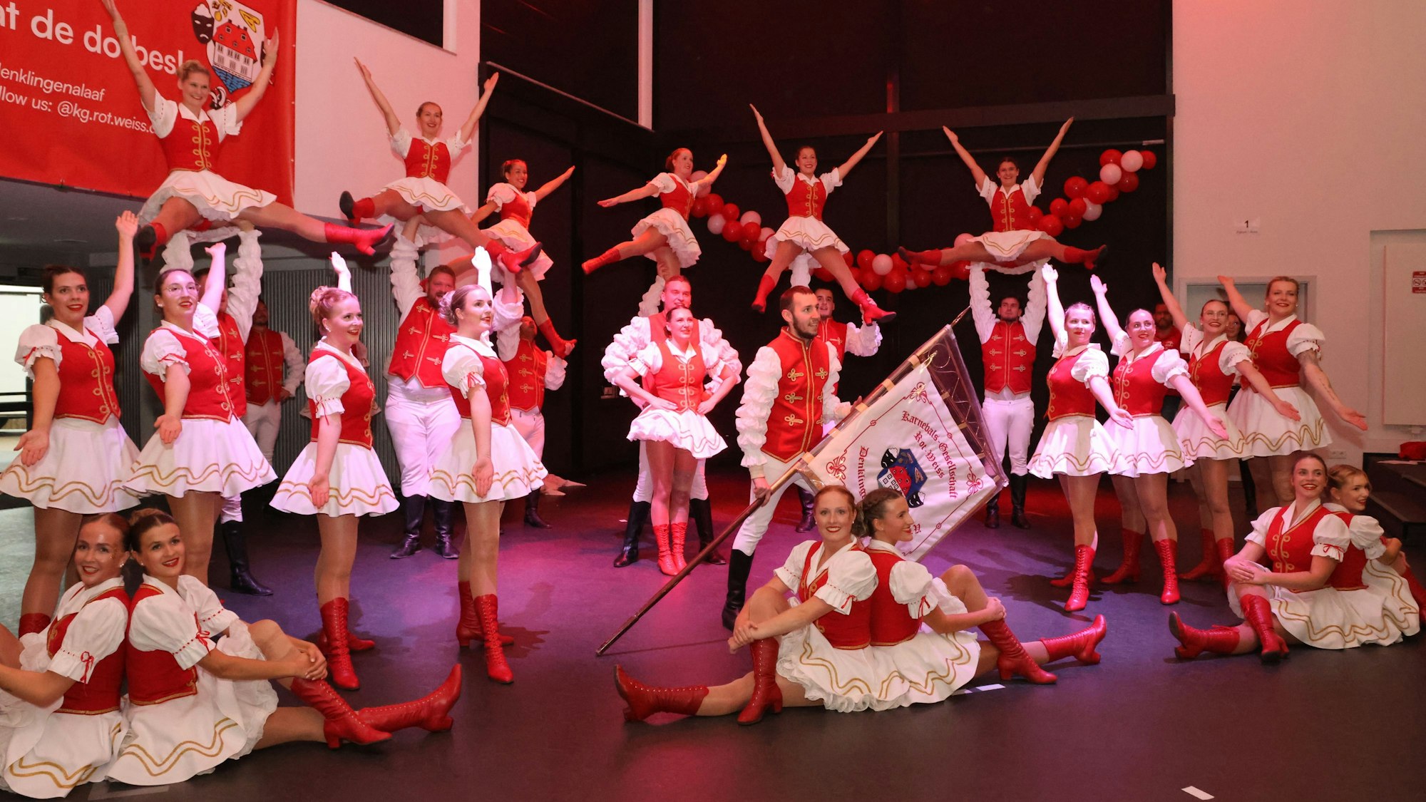 Im sitzen und im stehen, präsentiert sich eine Tanzgruppe auf der Bühne.