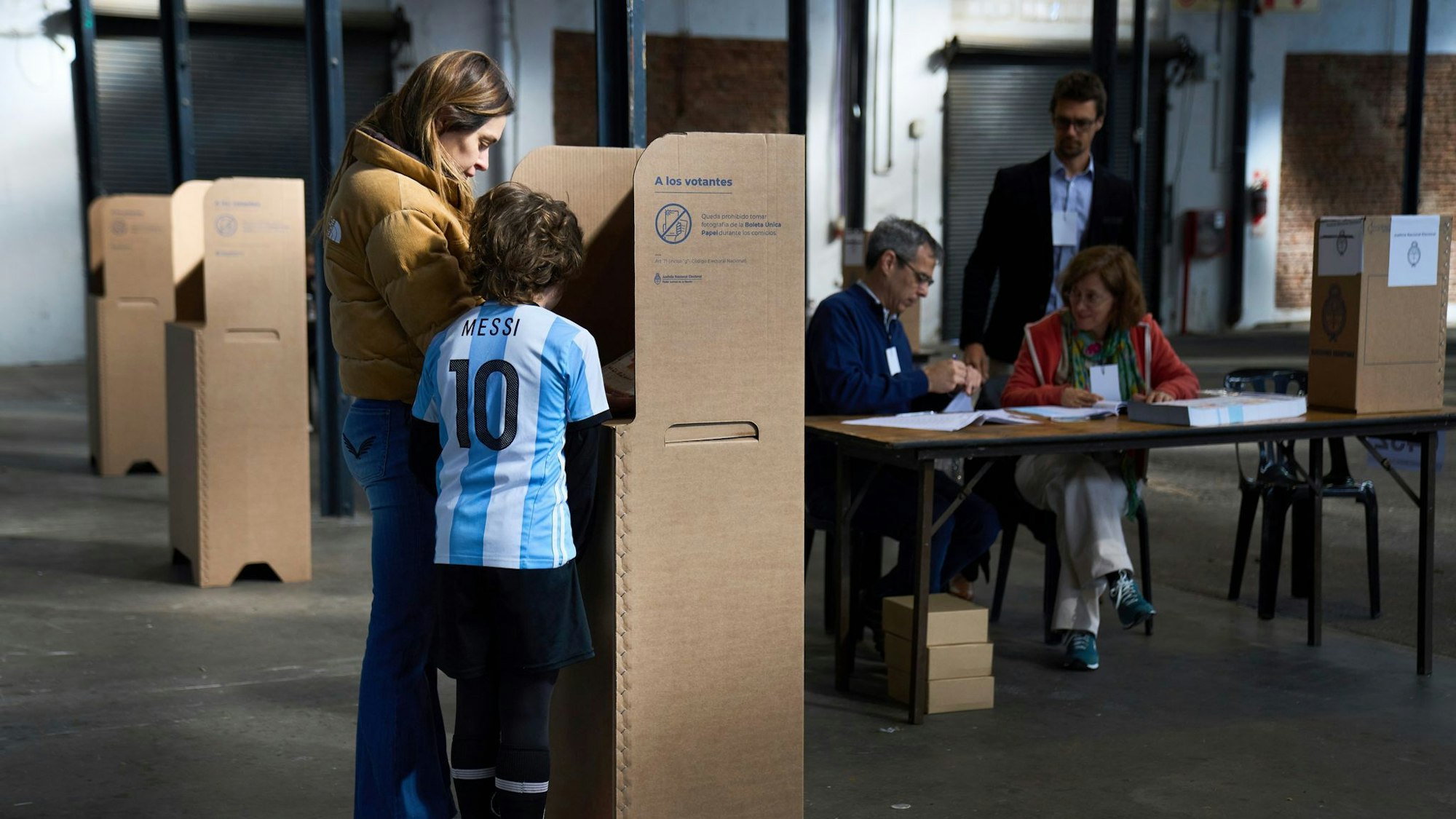Die Wahlkabinen in Argentinien sind fast leer, nur eine Frau und ein Junge stehen vor einer.