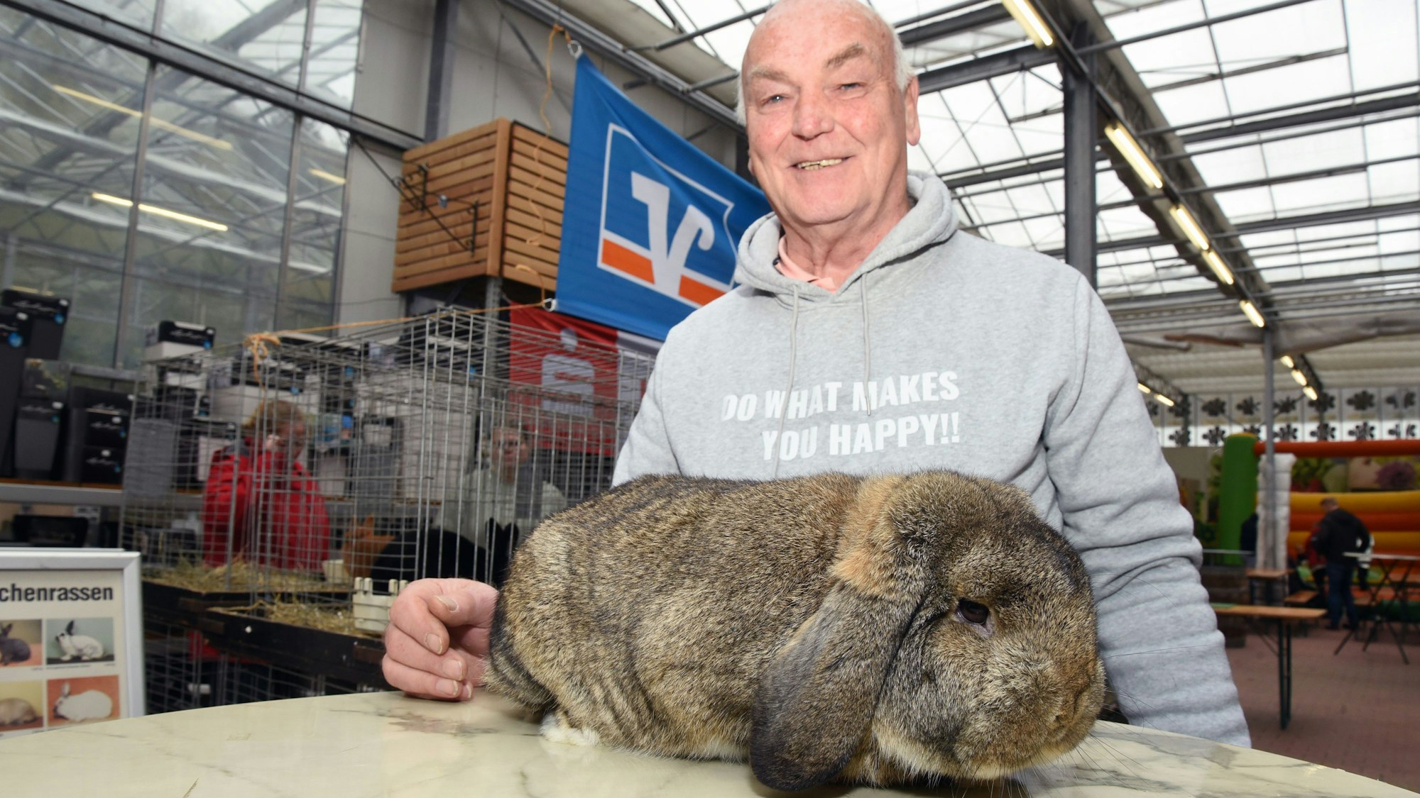 Ein Mann steht an einem Tisch, auf dem ein großes Kaninchen sitzt.
