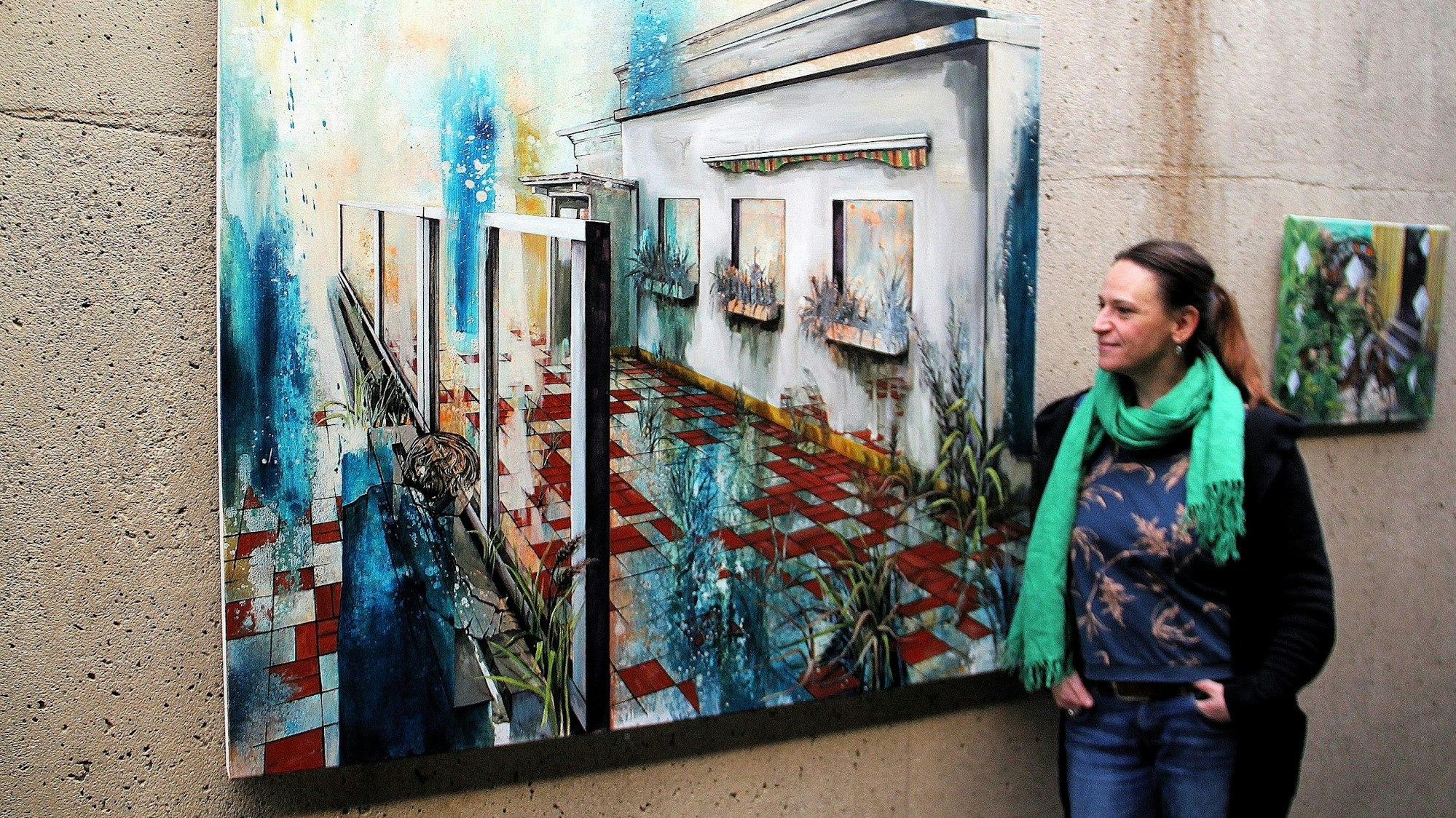 Eine Frau steht neben einem großformatigen Bild, das an einer rauen Kirchenwand hängt.