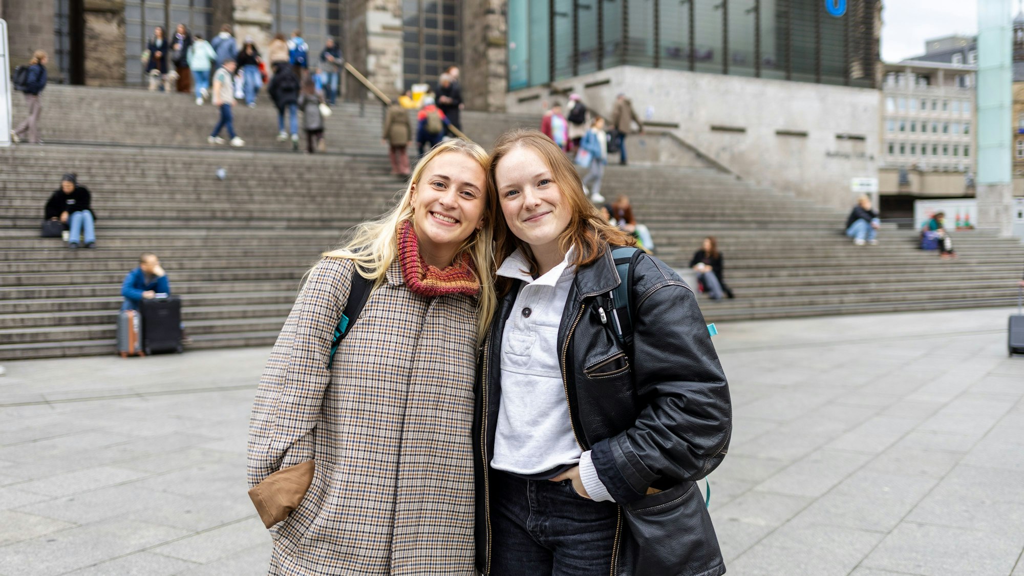 Zwei junge Frauen stehen Kopf an Kopf vor der Treppe zum Kölner Dom.