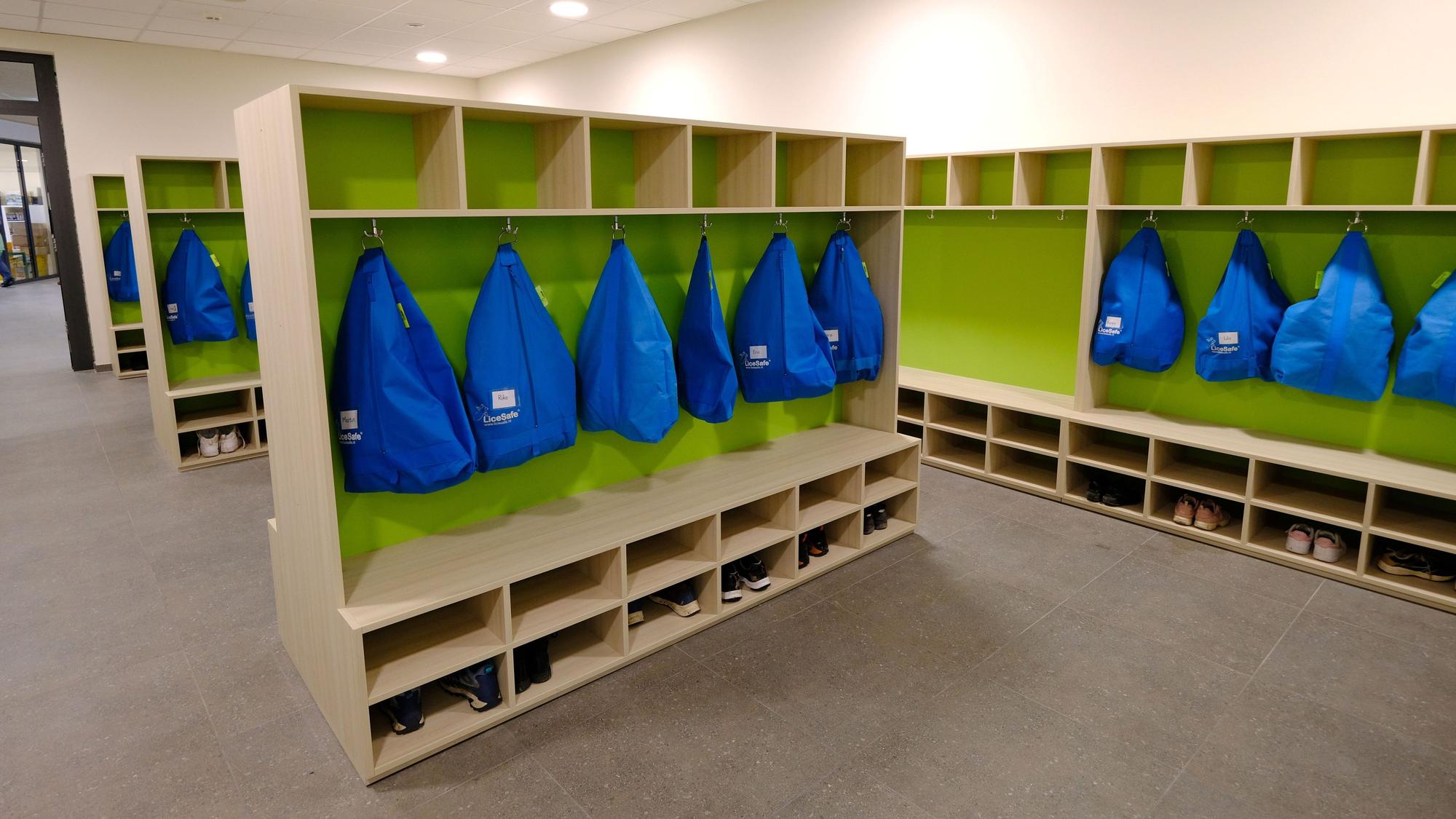 Im Garderobenraum der Gemeinschaftsgrundschule Firmenich-Obergartzem hängen blaue Kleidersäcke an den Haken.