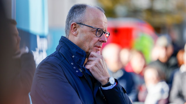 Bundeskanzler Friedrich Merz (CDU) hört sich bei einem Bürgergespräch in Meschede Fragen der Zuschauer an. Er sieht nachdenklich aus, berührt mit einer Hand sein Kinn.