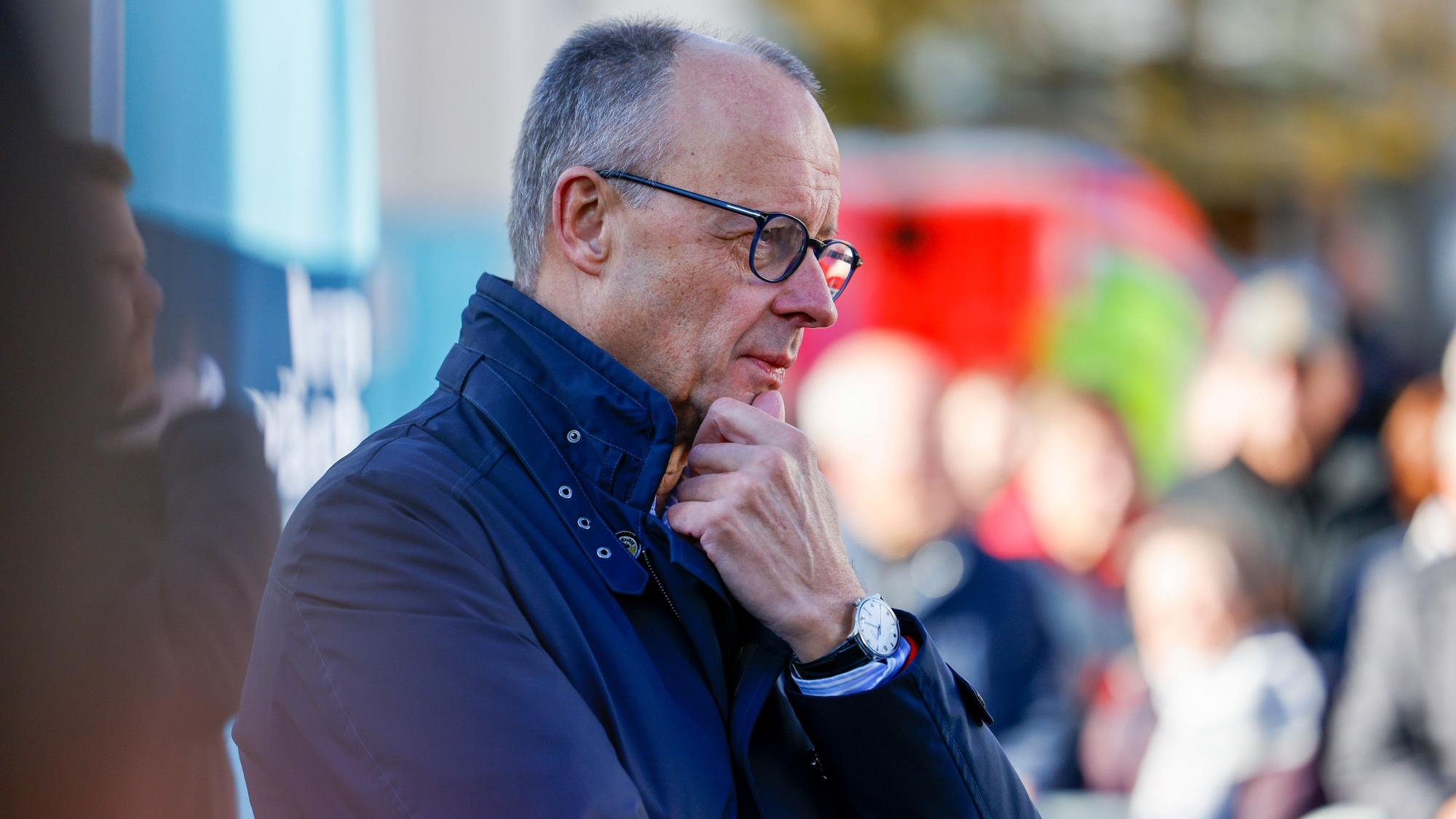 Bundeskanzler Friedrich Merz (CDU) hört sich bei einem Bürgergespräch in Meschede Fragen der Zuschauer an. Er sieht nachdenklich aus, berührt mit einer Hand sein Kinn.