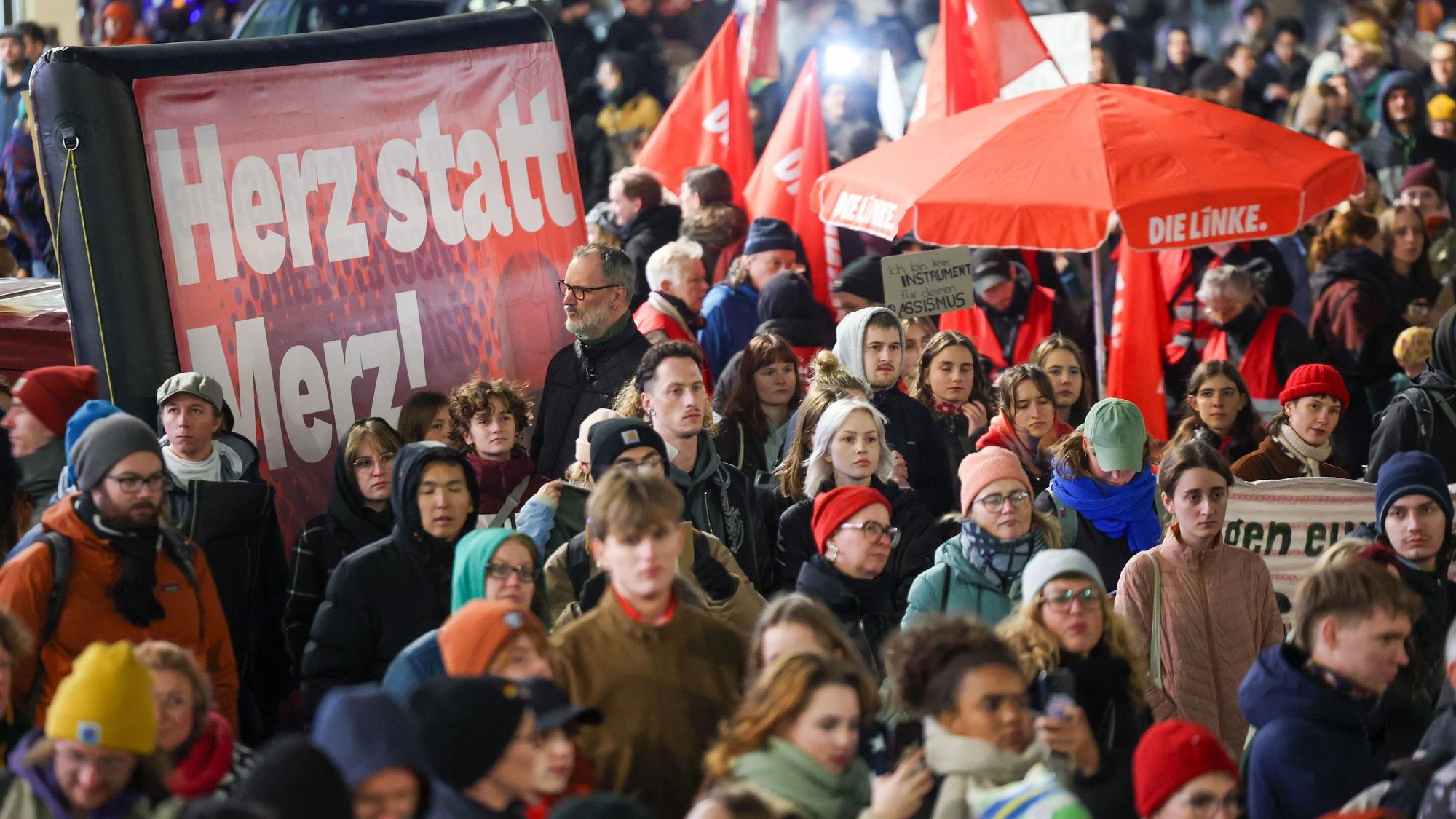 Teilnehmer der Demonstration «Das Stadtbild bleibt bunt» stehen neben einem Plakat mit der Aufschrift «Herz statt Merz!» auf dem Marktplatz von Leipzig.