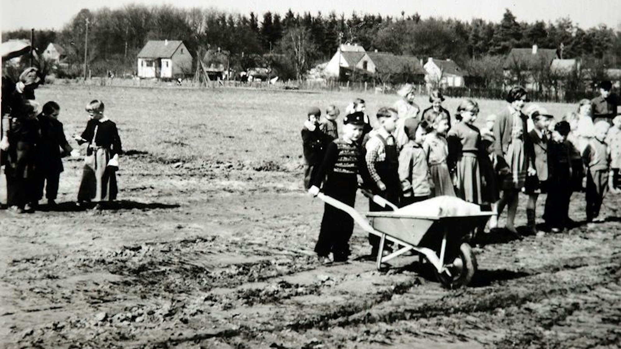 Ein historisches Foto, Kinder mit einer Schubkarre auf einem Baugrundstück.